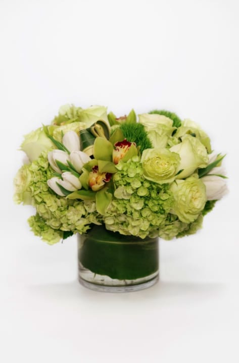 Green and white floral arrangement in a glass vase