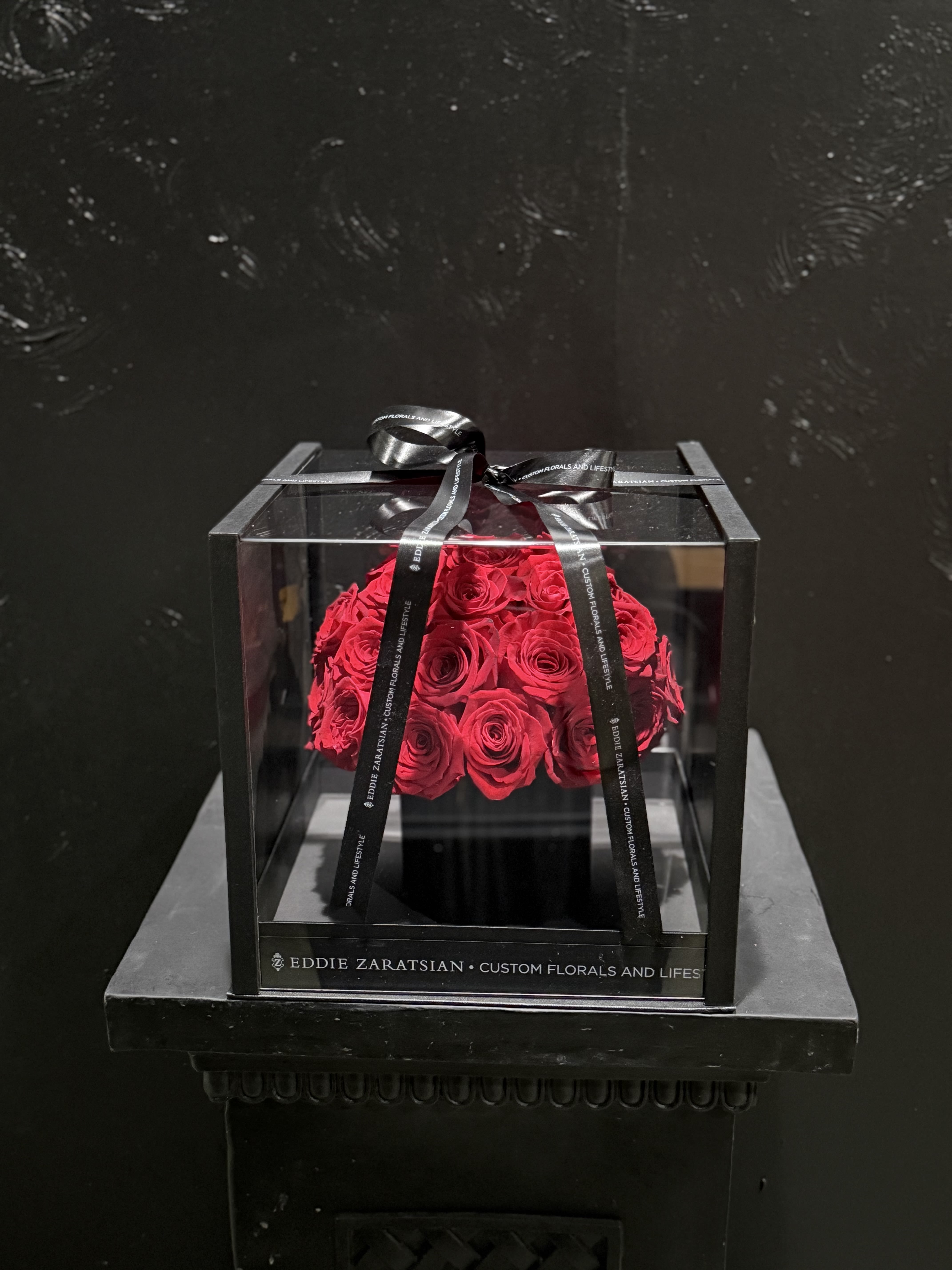 Red roses in a clear square box tied with a black ribbon