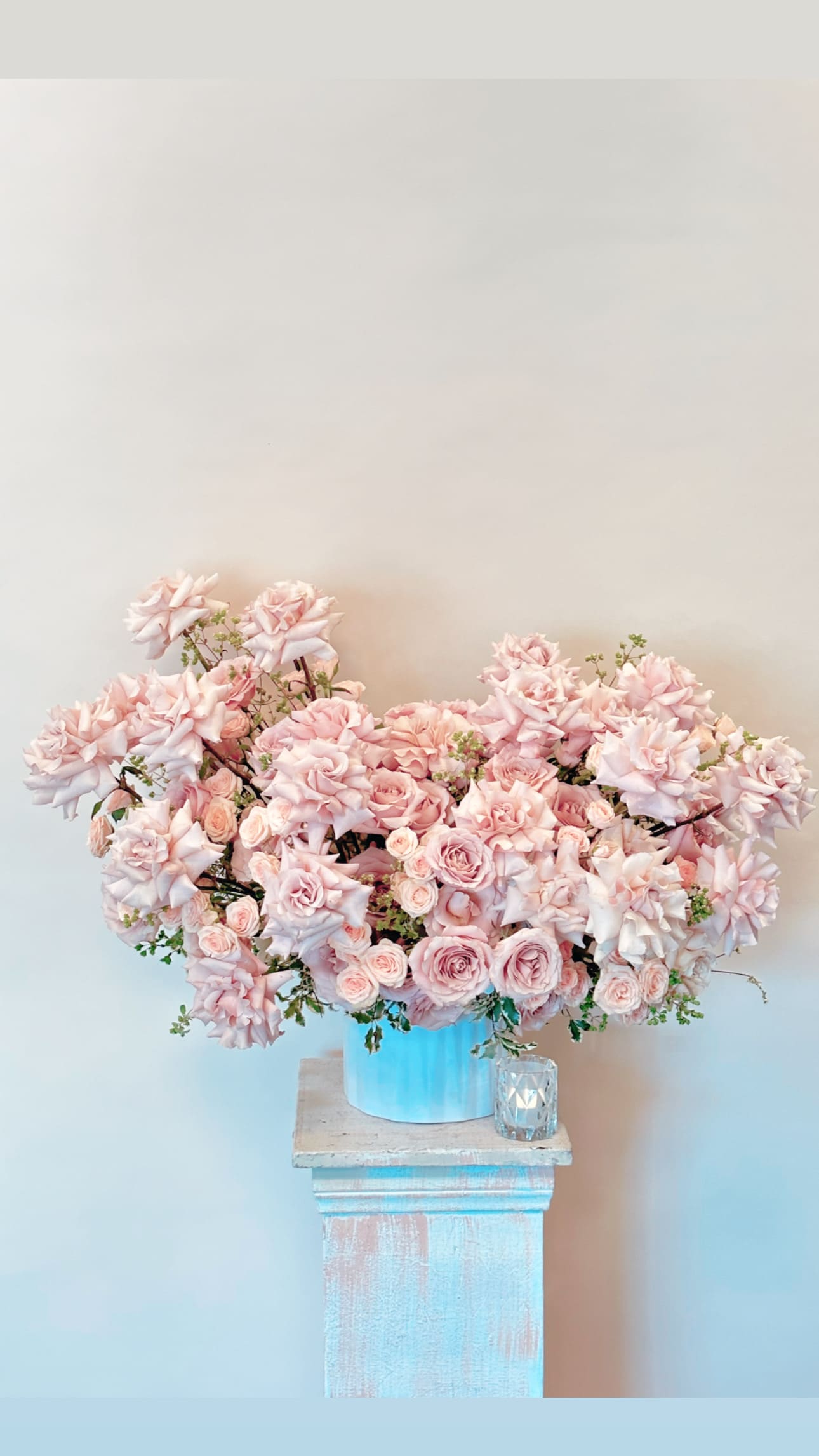 Large pink rose arrangement in a blue container on a pedestal