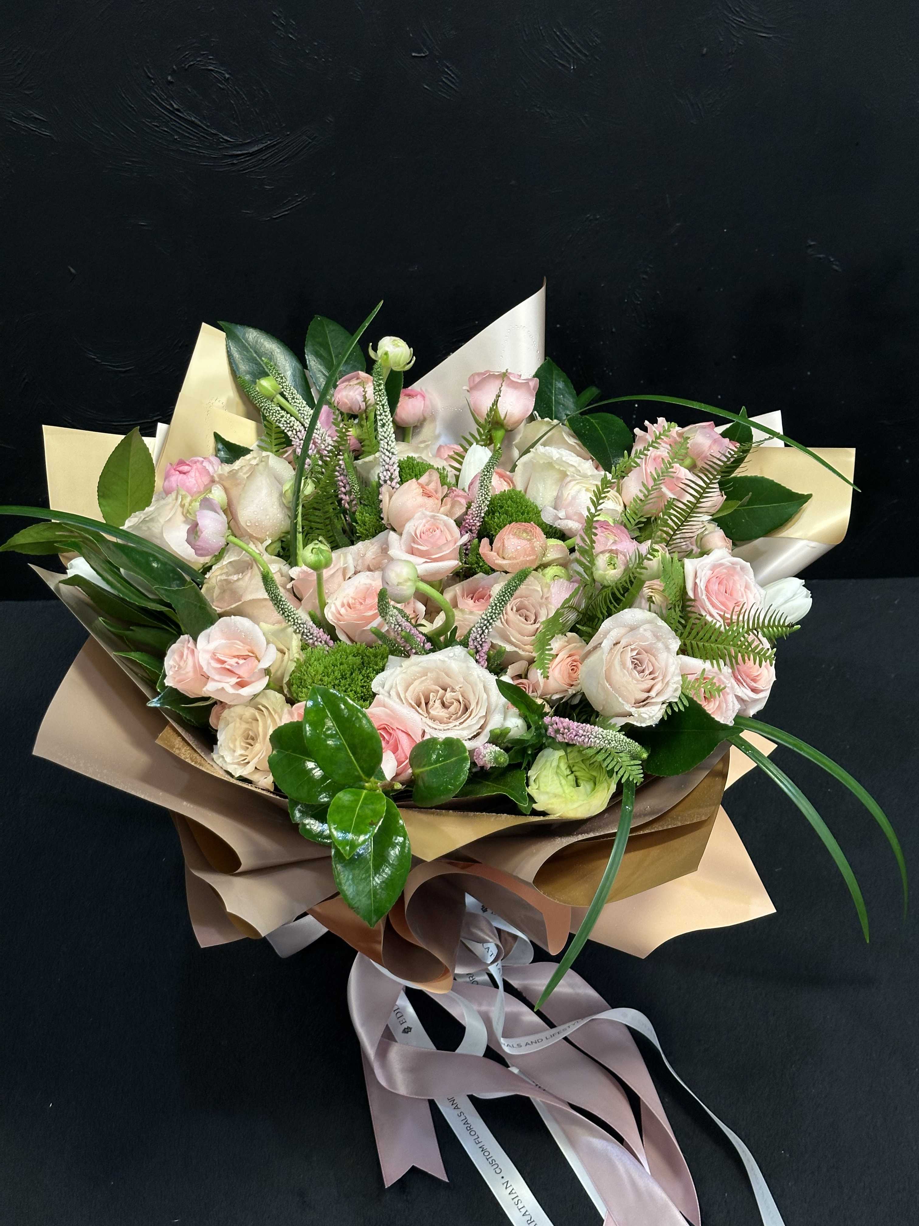 Bouquet of pale pink and white roses wrapped in tan paper
