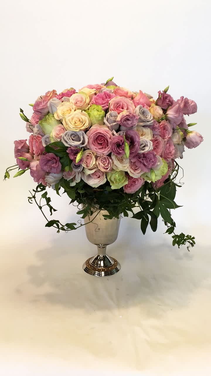 Large pastel rose arrangement in a silver pedestal vase