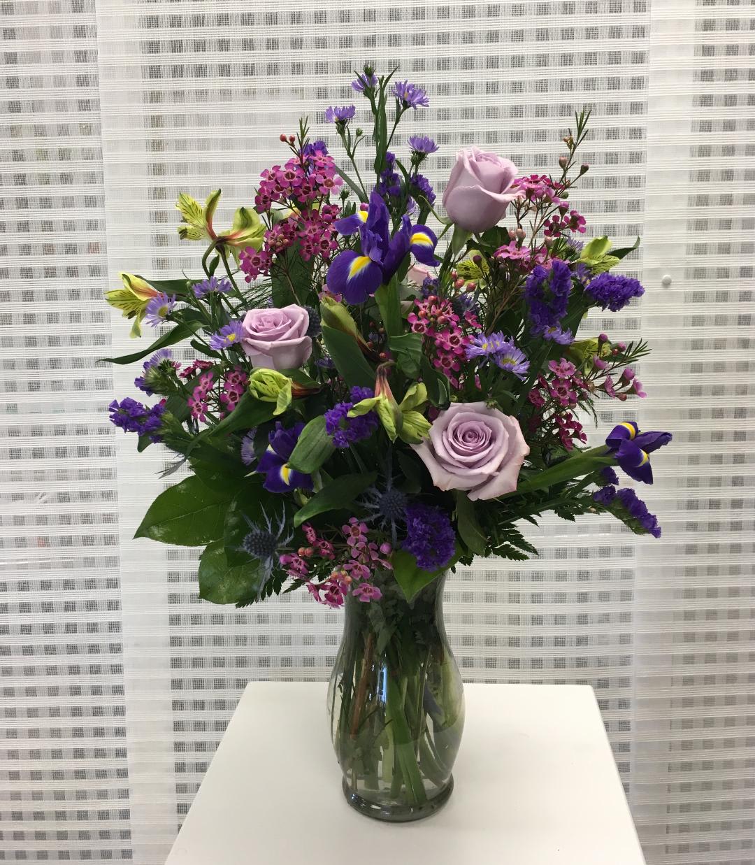Mixed bouquet of purple and pink flowers in a glass vase