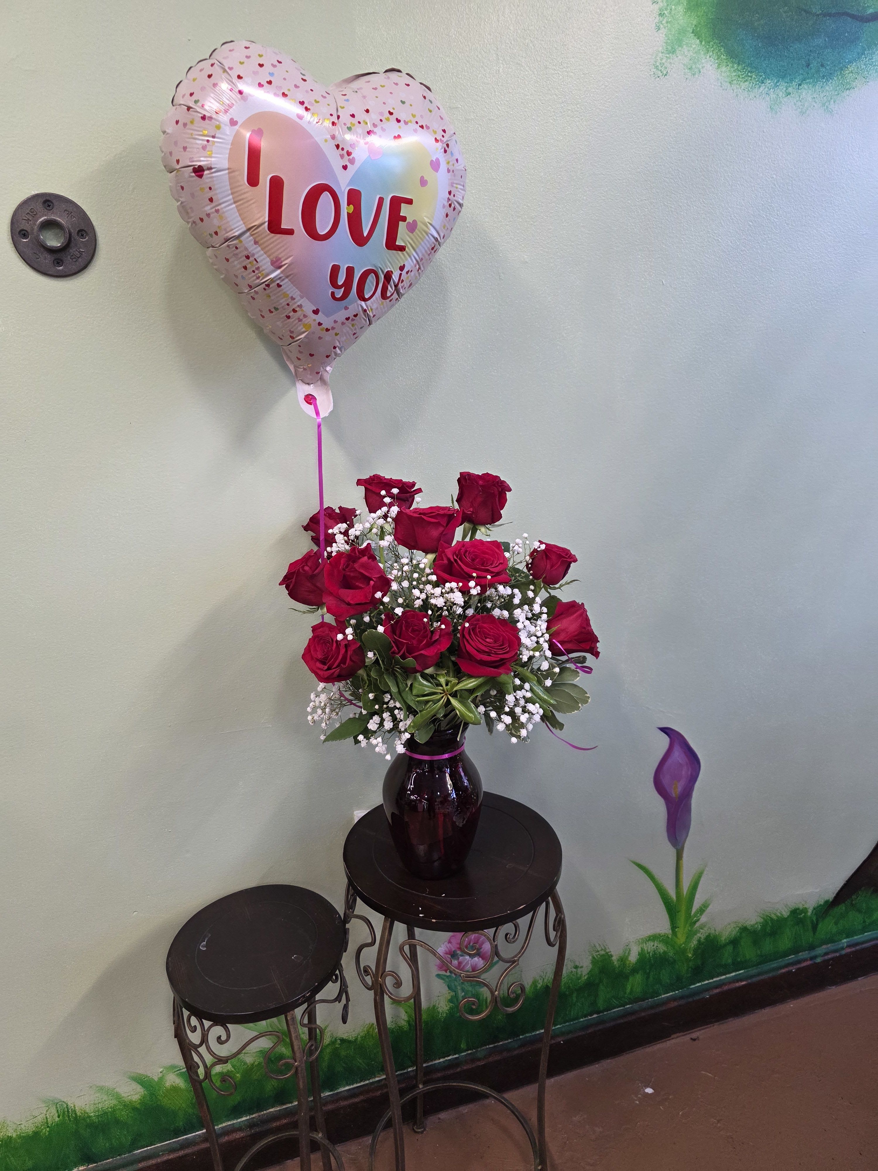 Red rose bouquet in a vase with a heart-shaped "I love you" balloon