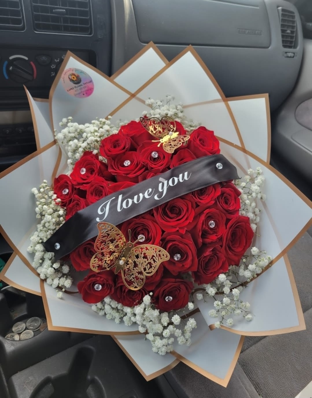 Red rose bouquet with baby’s breath and a black ribbon reading "I love you"