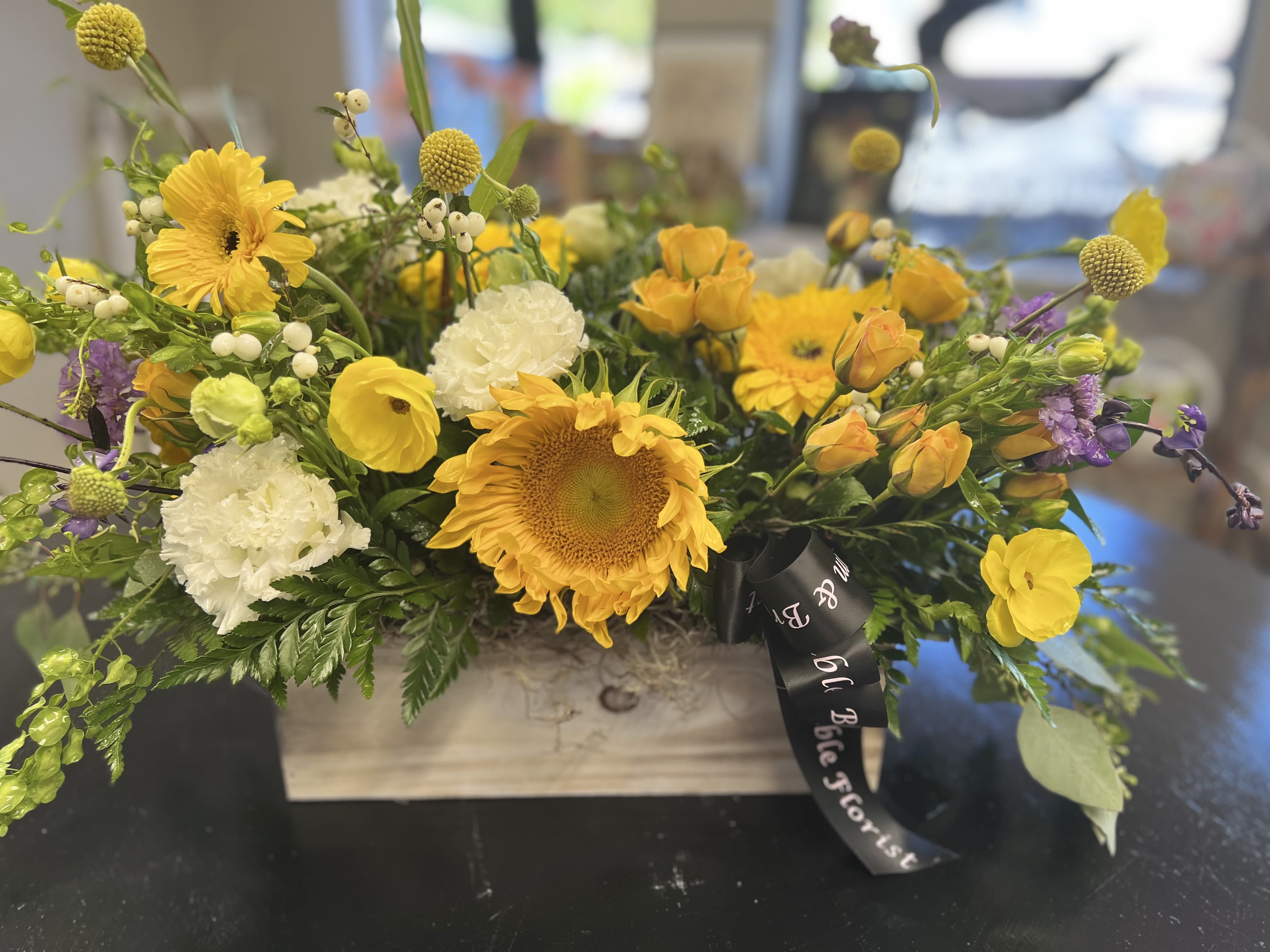 Yellow and white mixed flower arrangement in a wooden box