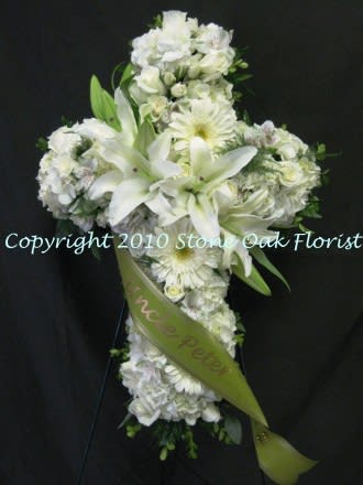 White floral cross arrangement with lilies and daisies on a black background
