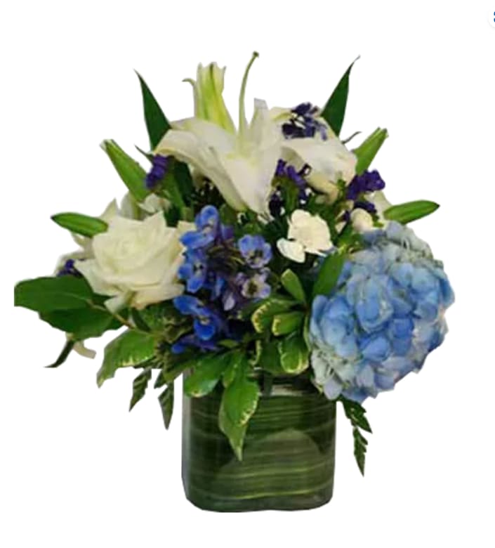 Many Wishes - ALL1146 - The Birthday Wishes arrangement is perfect for any occasion. It features a blue and white centerpiece filled with lilies, roses, hydrangea, delphinium and more.  Components may vary.  Shown in Deluxe  Many Wishes - ALL1146  Components may vary. Shown in Deluxe  ALL1146