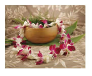 Pink and white orchid lei draped around a wooden bowl