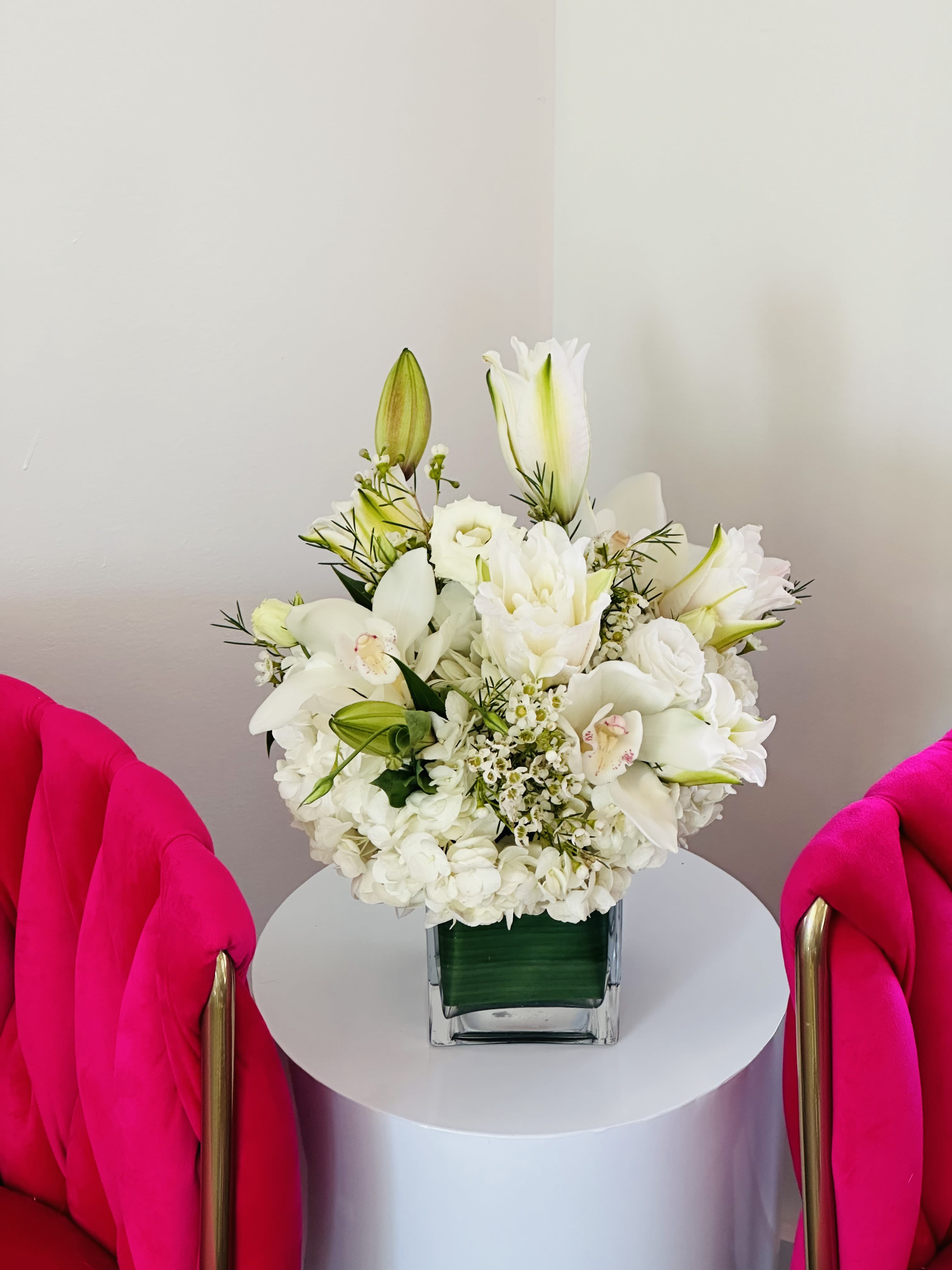 White floral arrangement in a square glass vase on a round table
