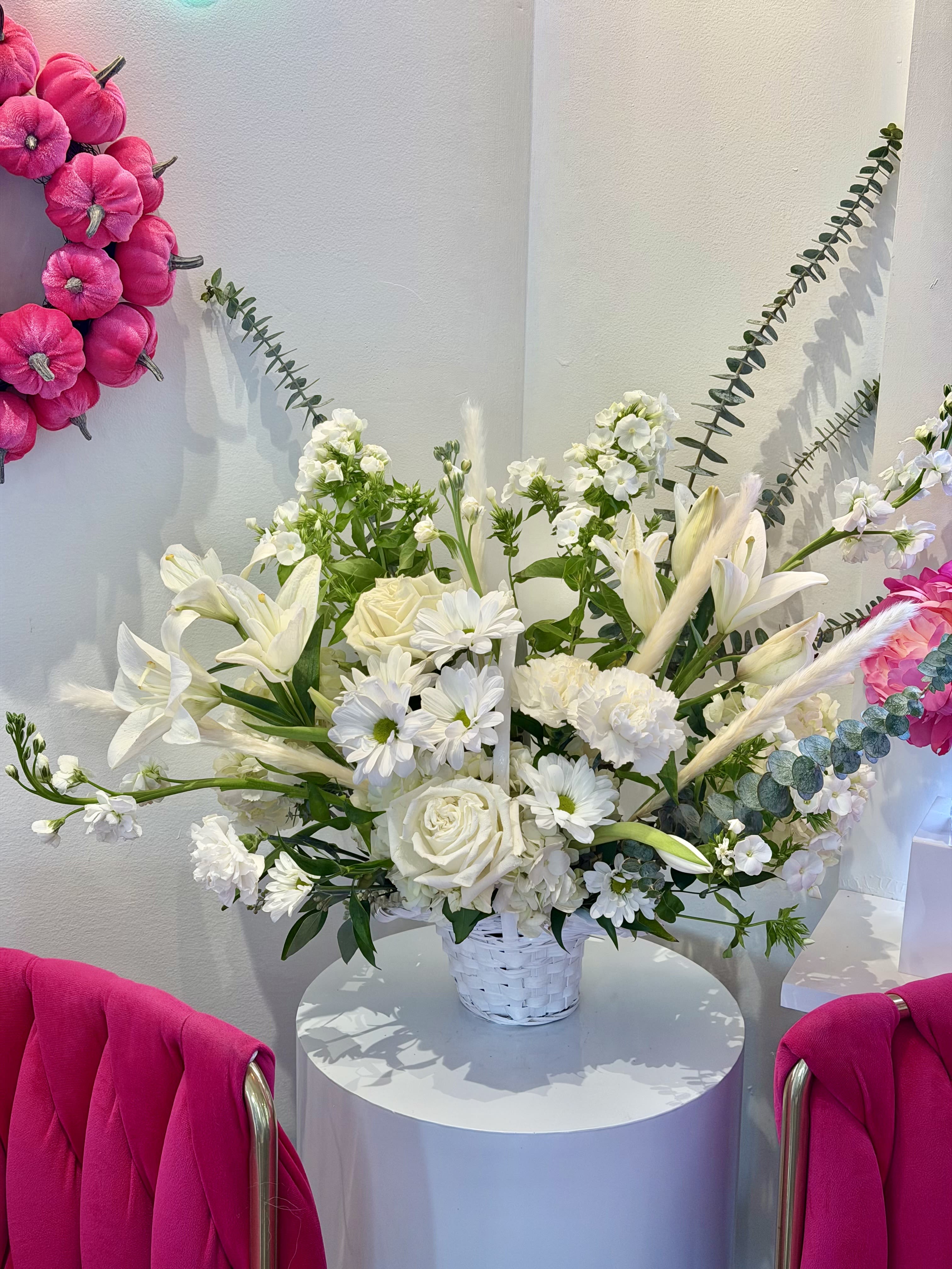White floral arrangement in a white basket with pink wall accents