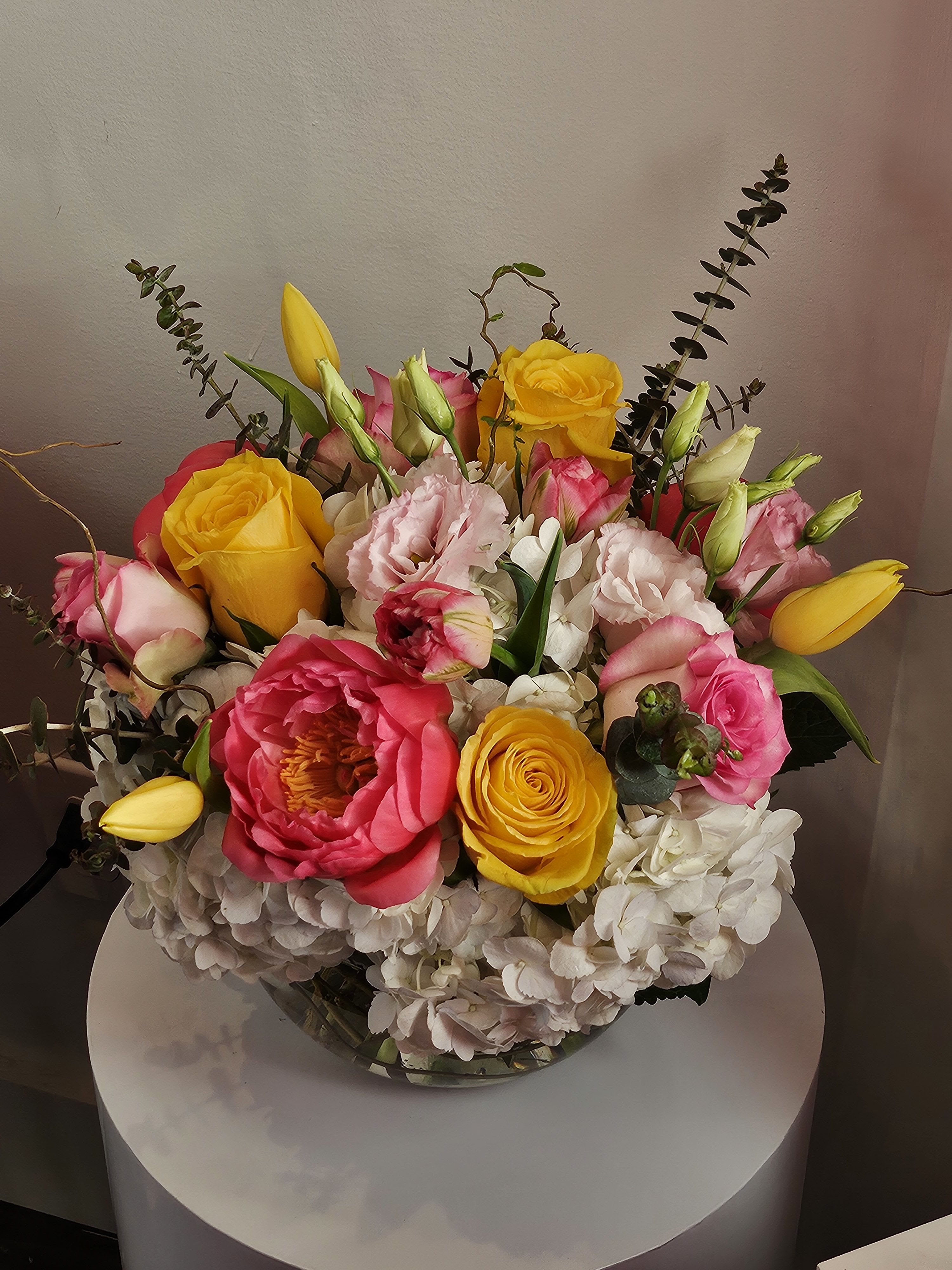 Bouquet of pink and yellow roses with white hydrangeas in a glass vase