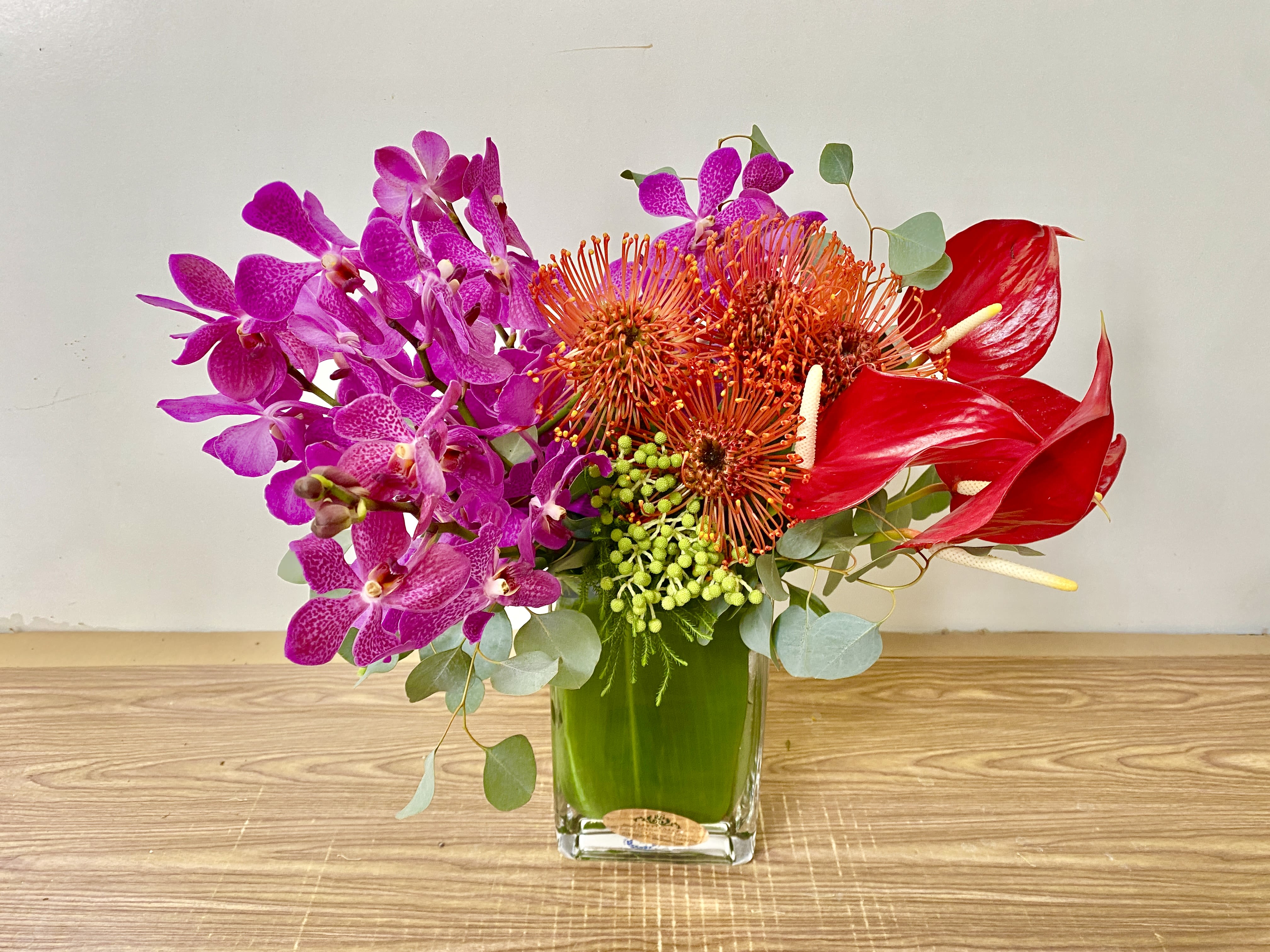 Bright orchid and anthurium arrangement in a glass vase
