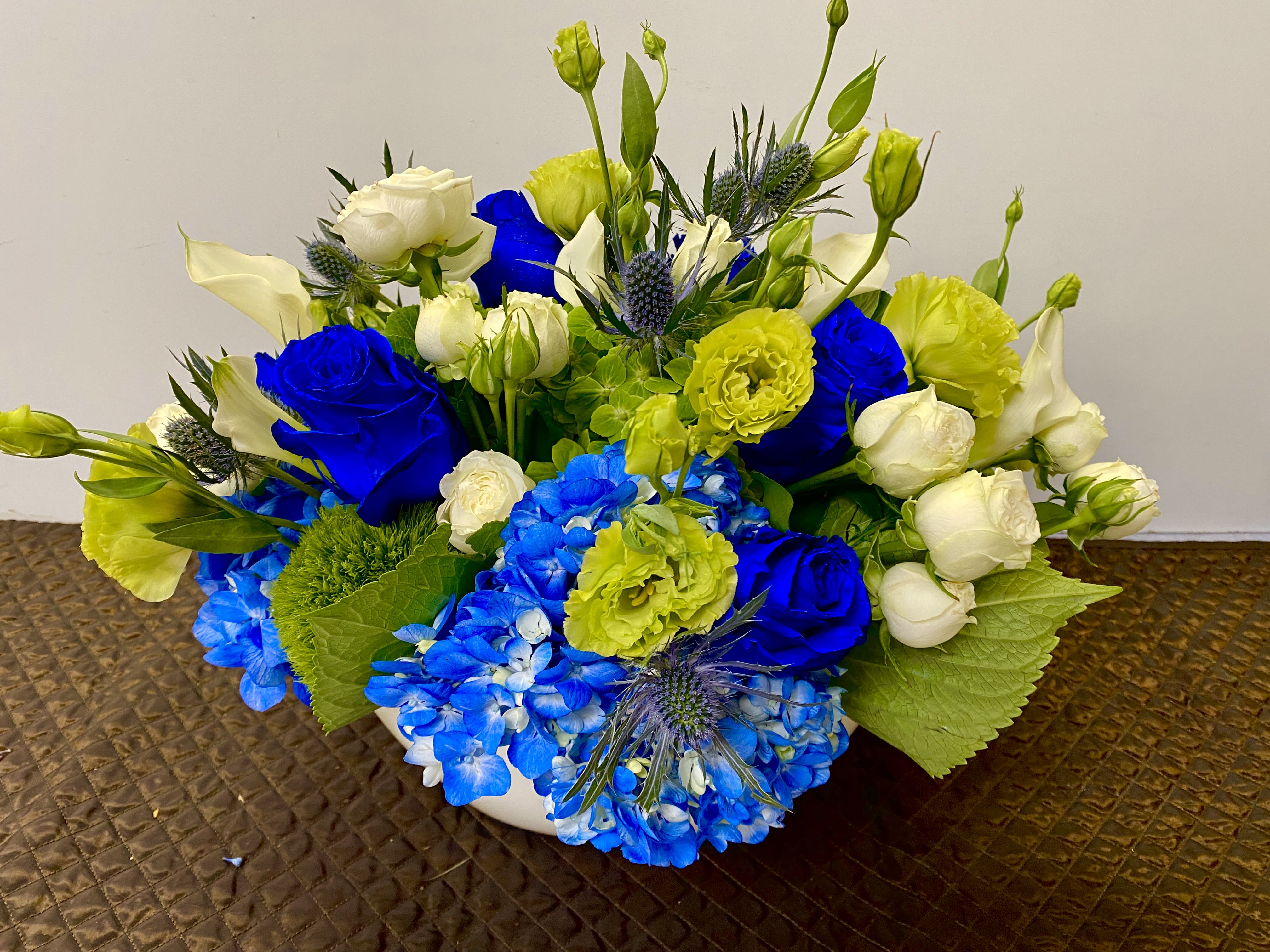 Blue and white floral arrangement with yellow accents in a white bowl