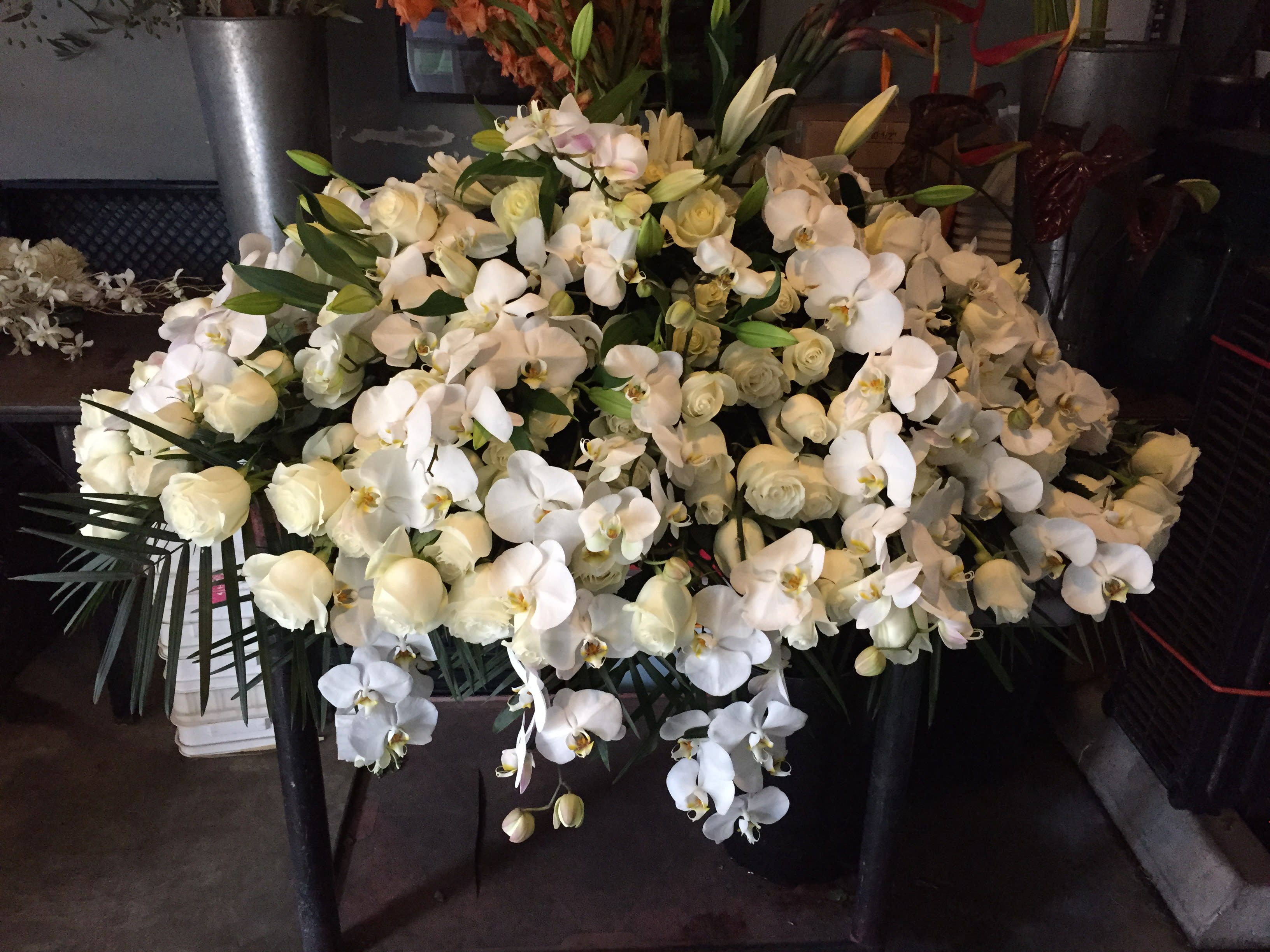 Large white orchid and rose arrangement in a black container