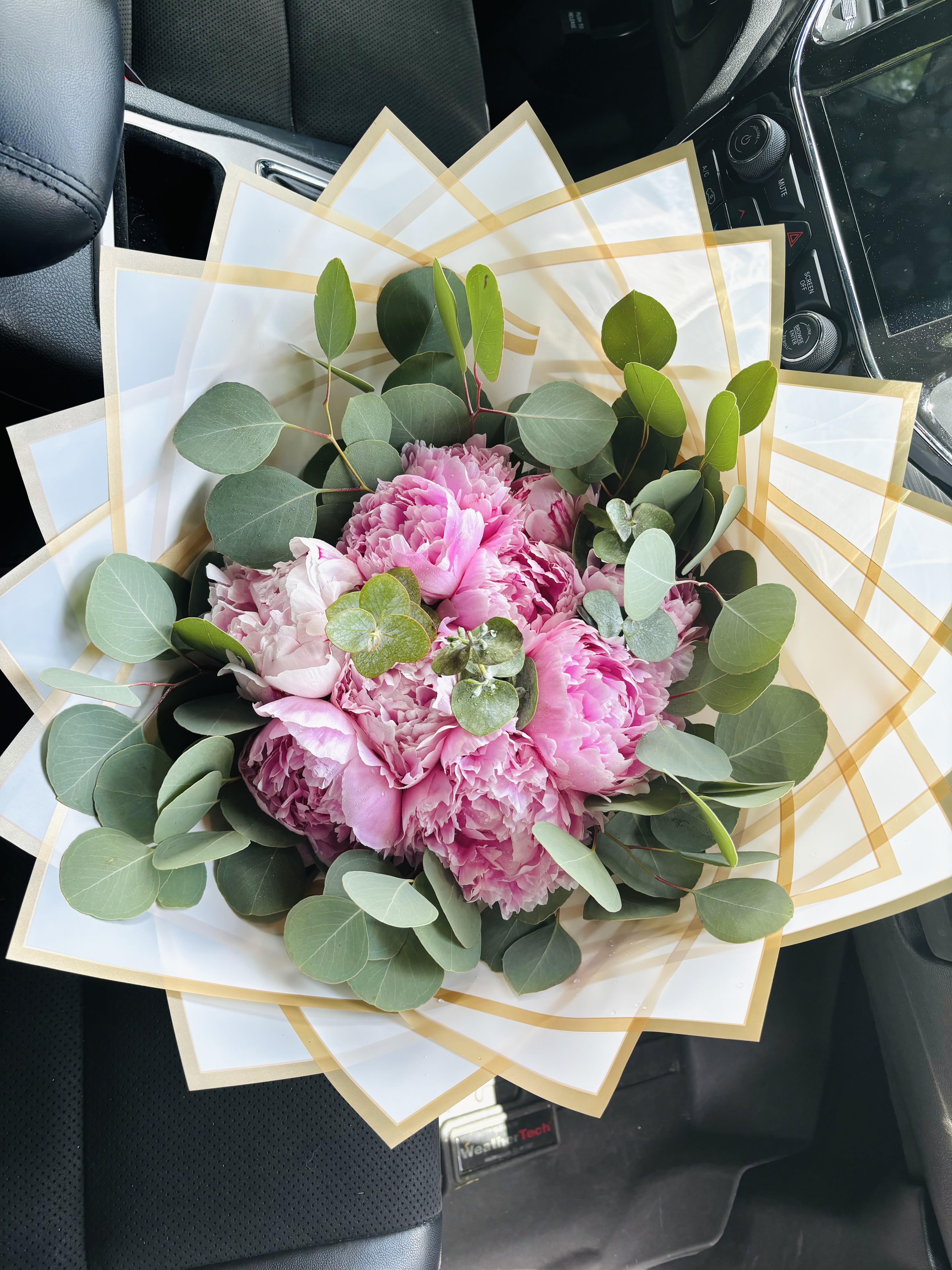 Pink peony bouquet wrapped in white paper with gold trim