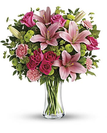 Pink lilies and roses arranged in a clear glass vase