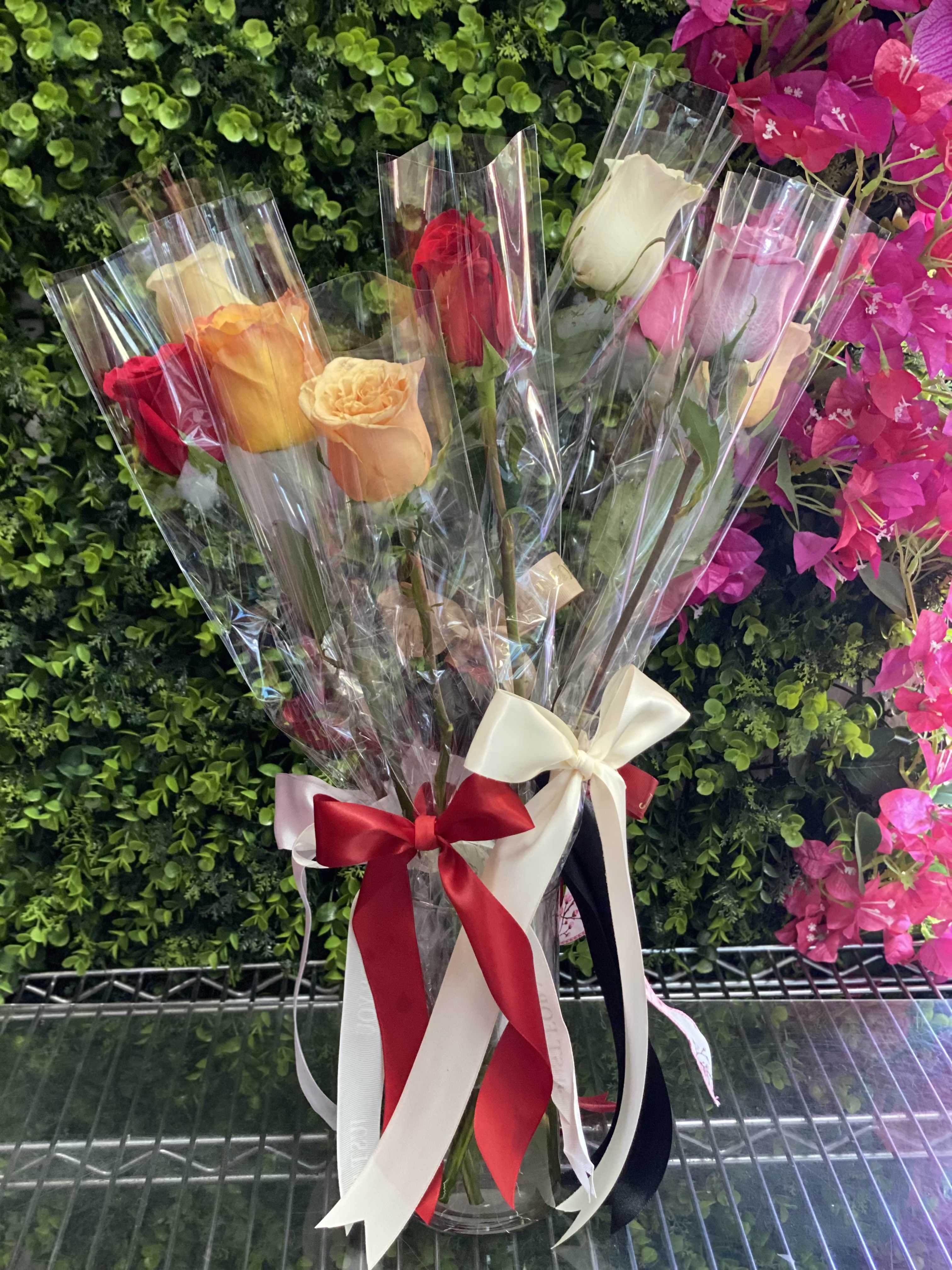 Bouquet of multicolored roses wrapped in clear plastic with satin ribbons