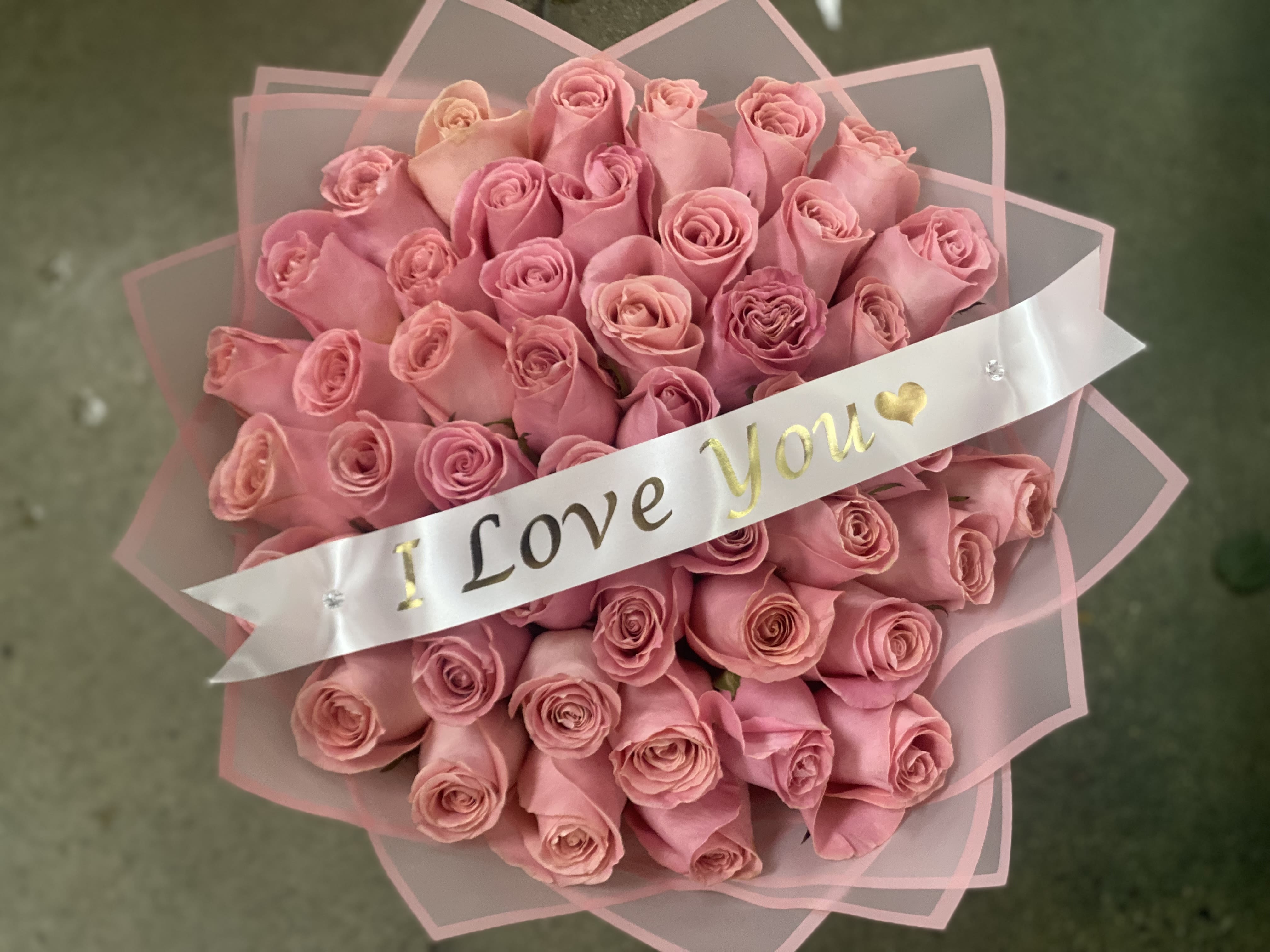 Bouquet of pink roses wrapped with a ribbon that says "I Love You"