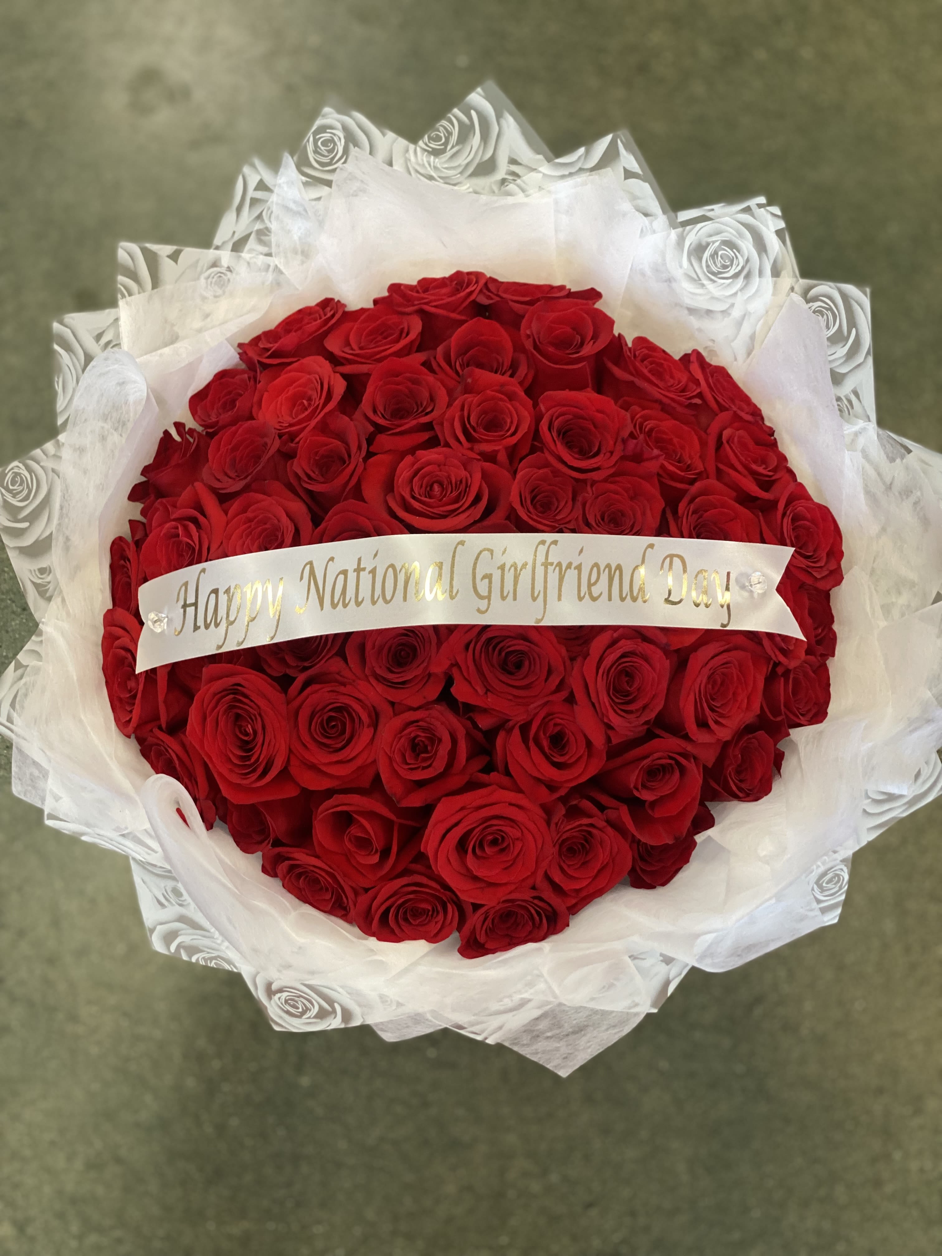 Bouquet of red roses wrapped in white paper with a ribbon