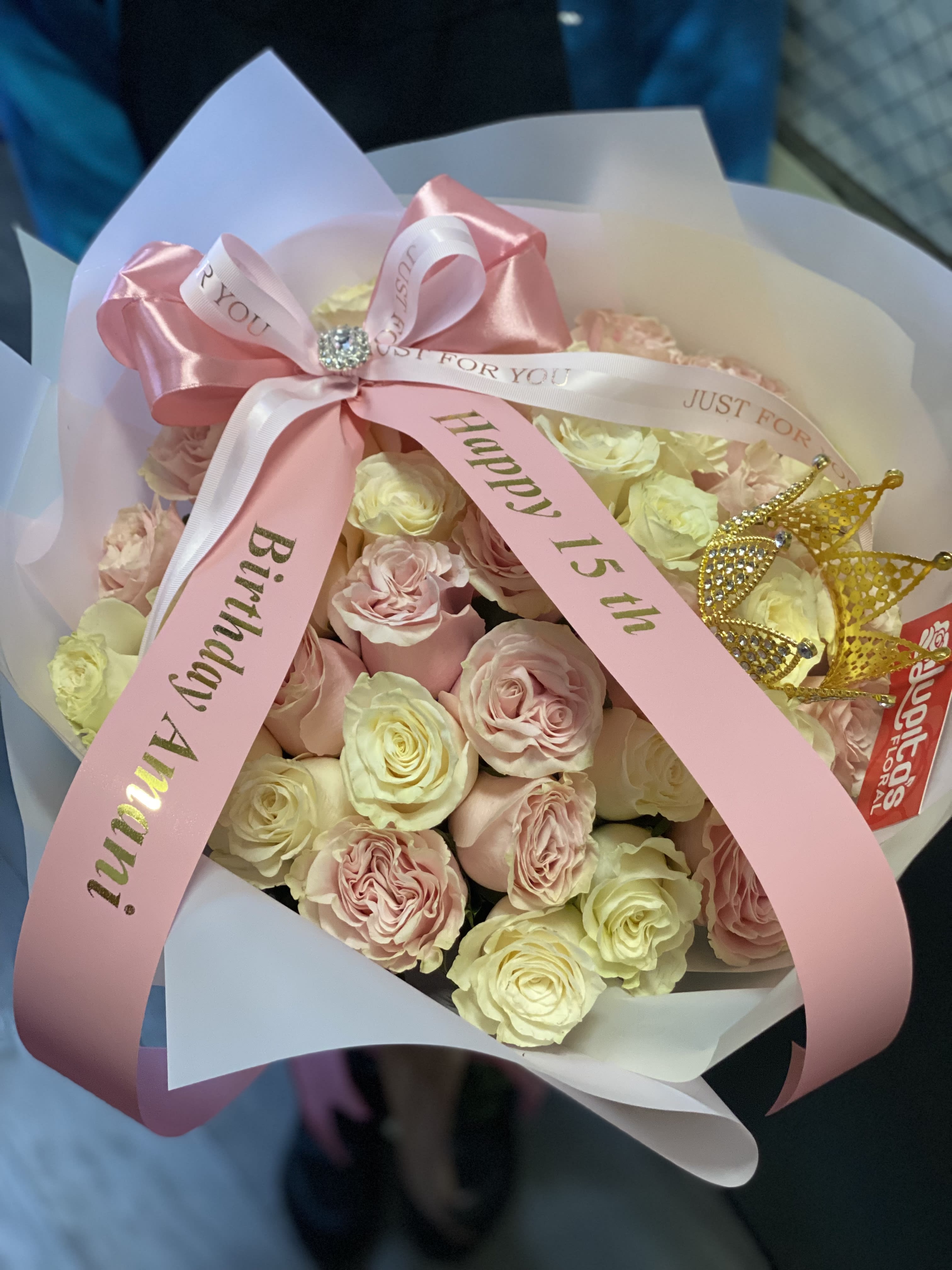 Pink and cream rose bouquet with birthday ribbons and a gold crown topper