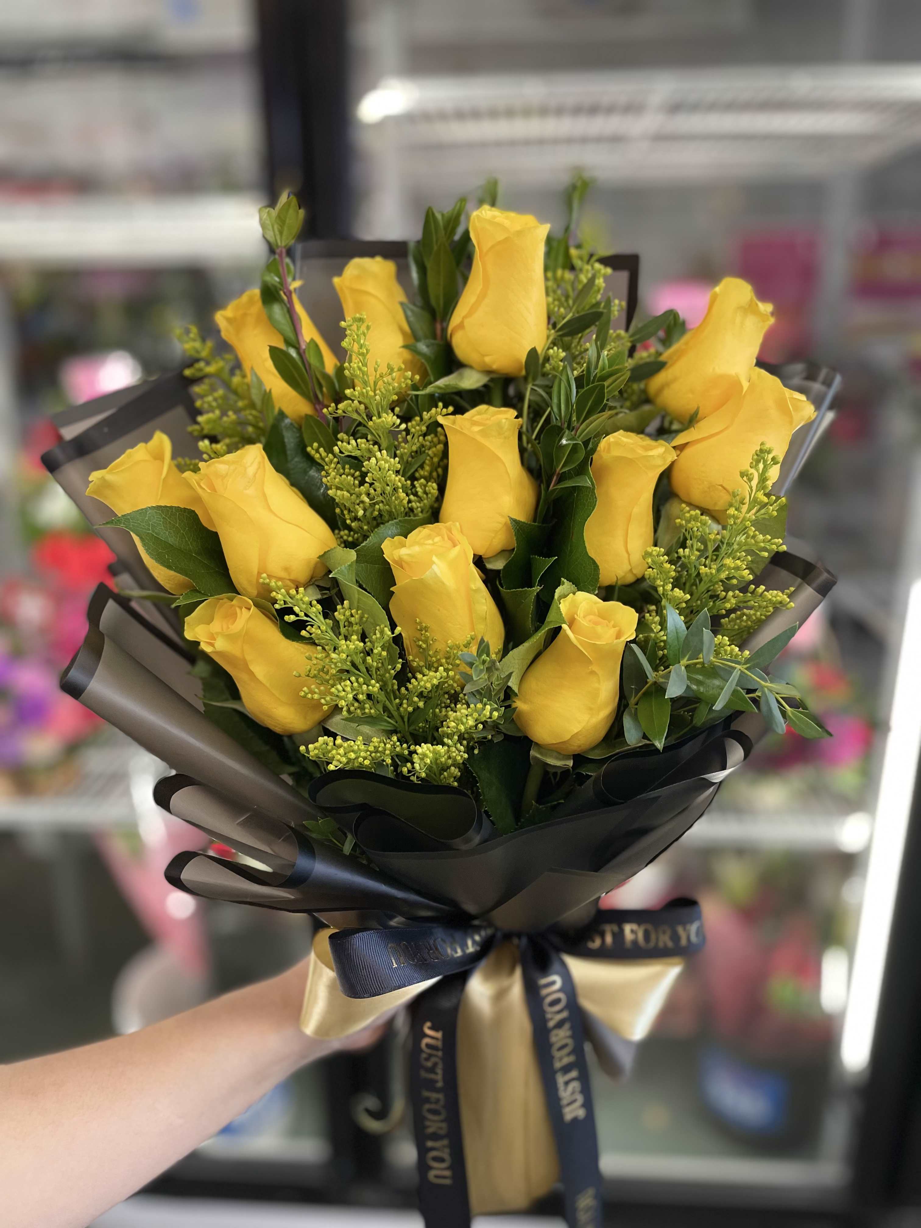 Bouquet of yellow roses wrapped in black paper with a ribbon