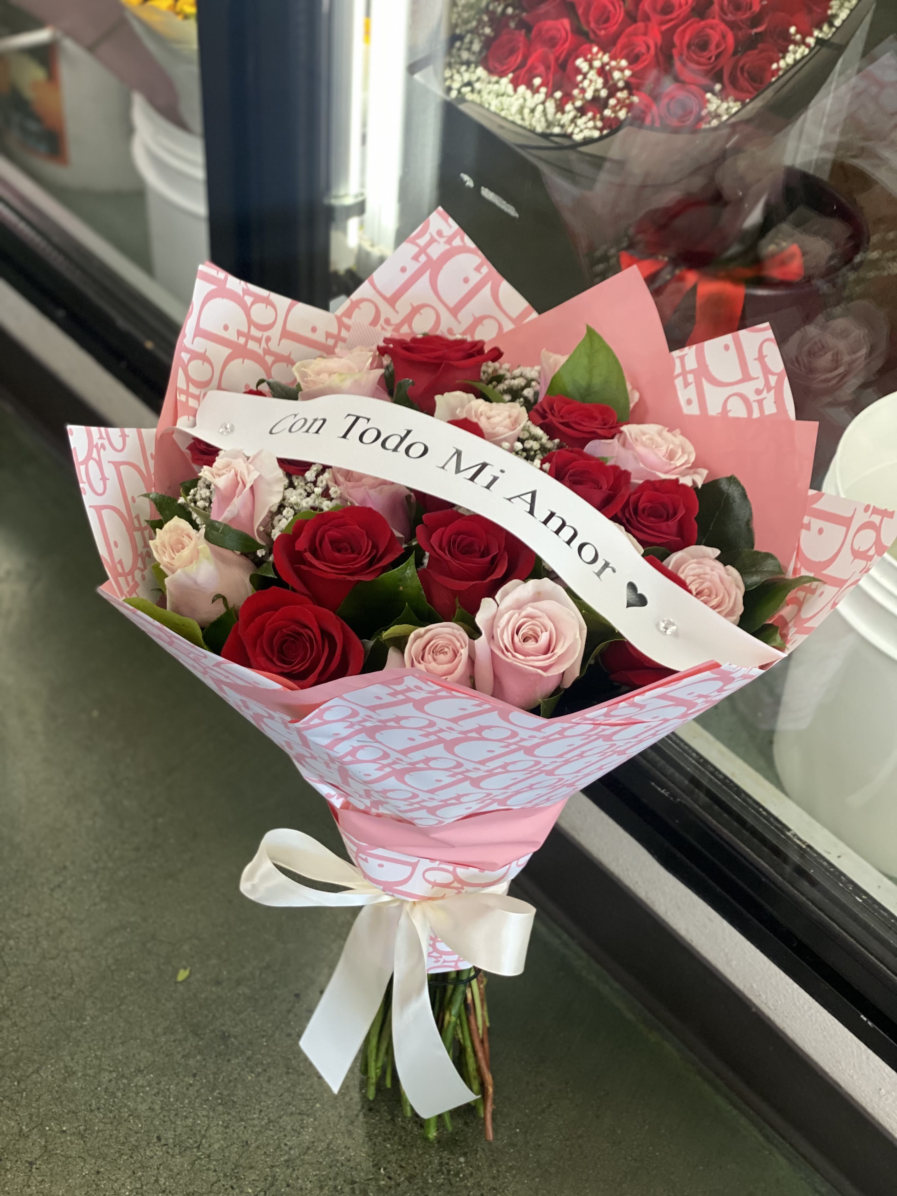 Bouquet of red and pink roses with a ribbon reading "Con Todo Mi Amor"