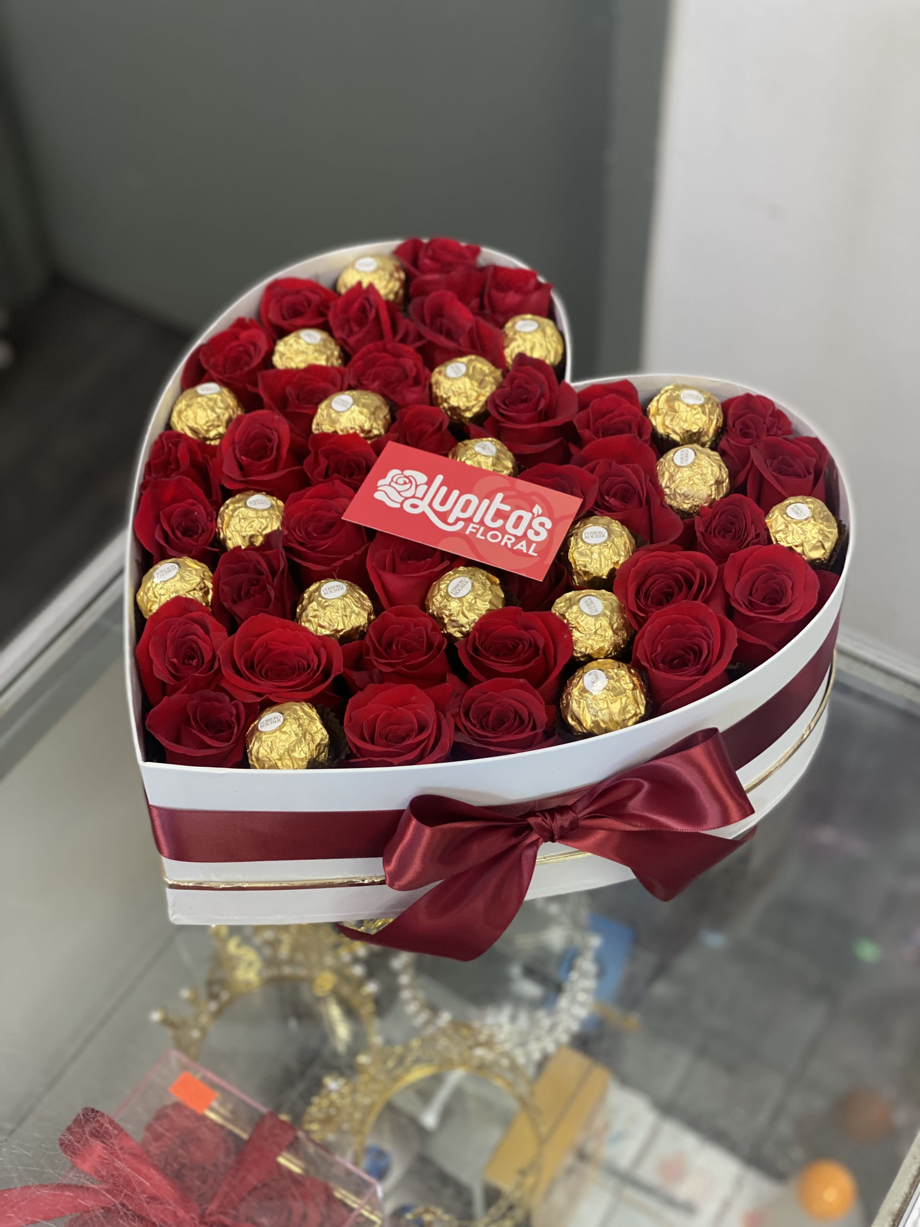 Heart-shaped box of red roses and gold-wrapped chocolates with a satin bow