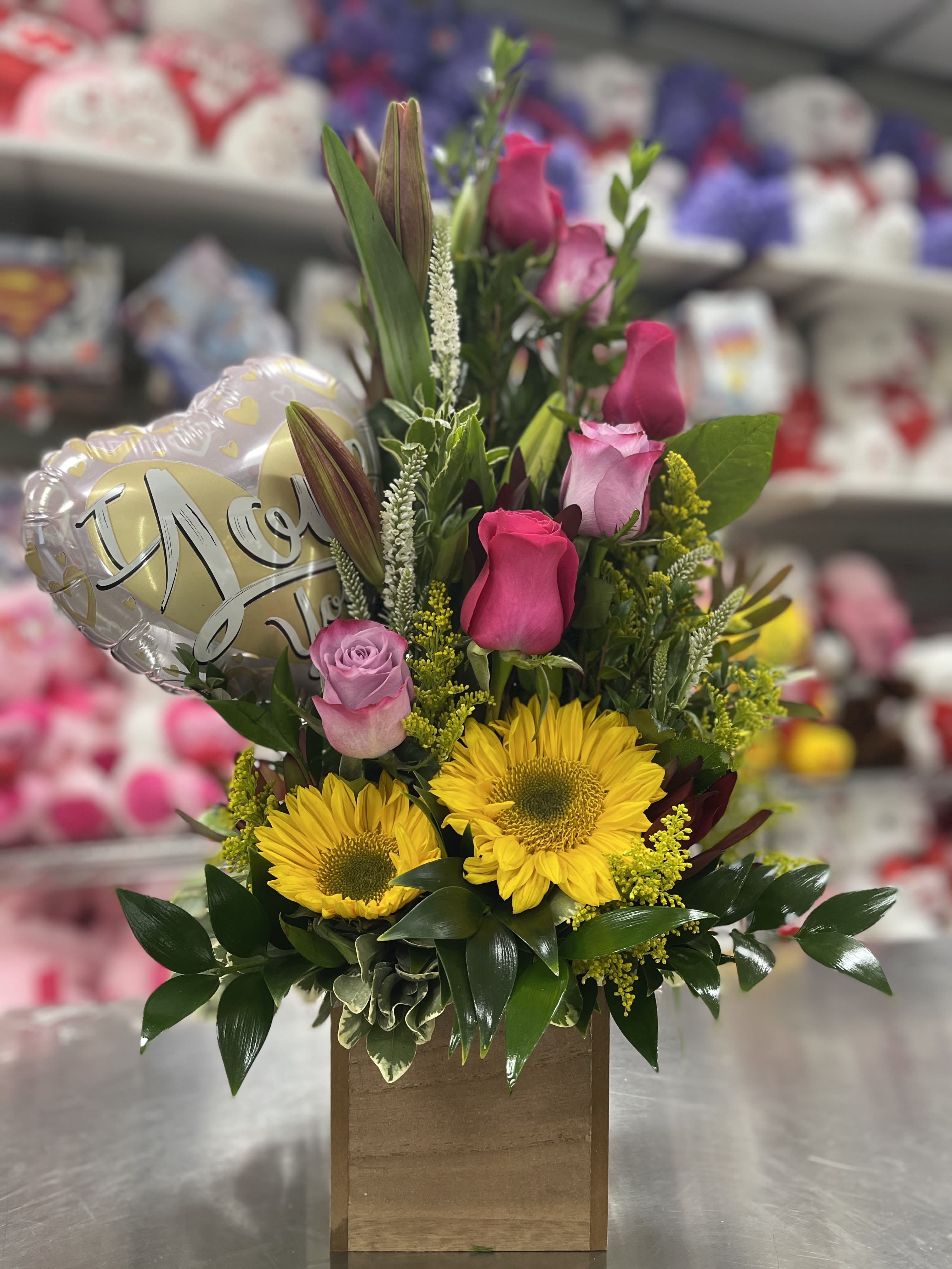 Mixed bouquet with yellow sunflowers, pink roses, and a heart balloon in a wooden box