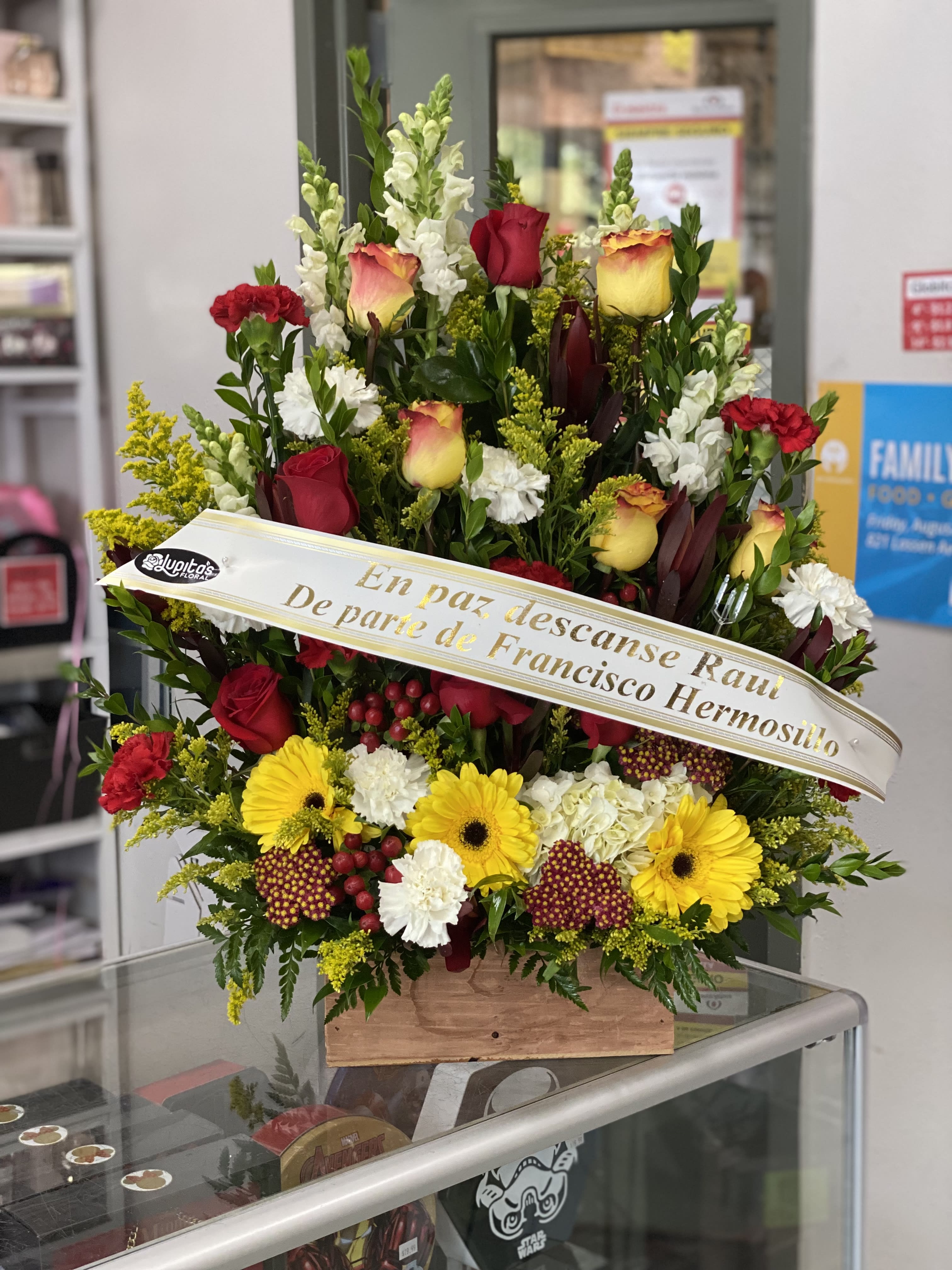 Large sympathy spray with red and yellow flowers and a memorial ribbon