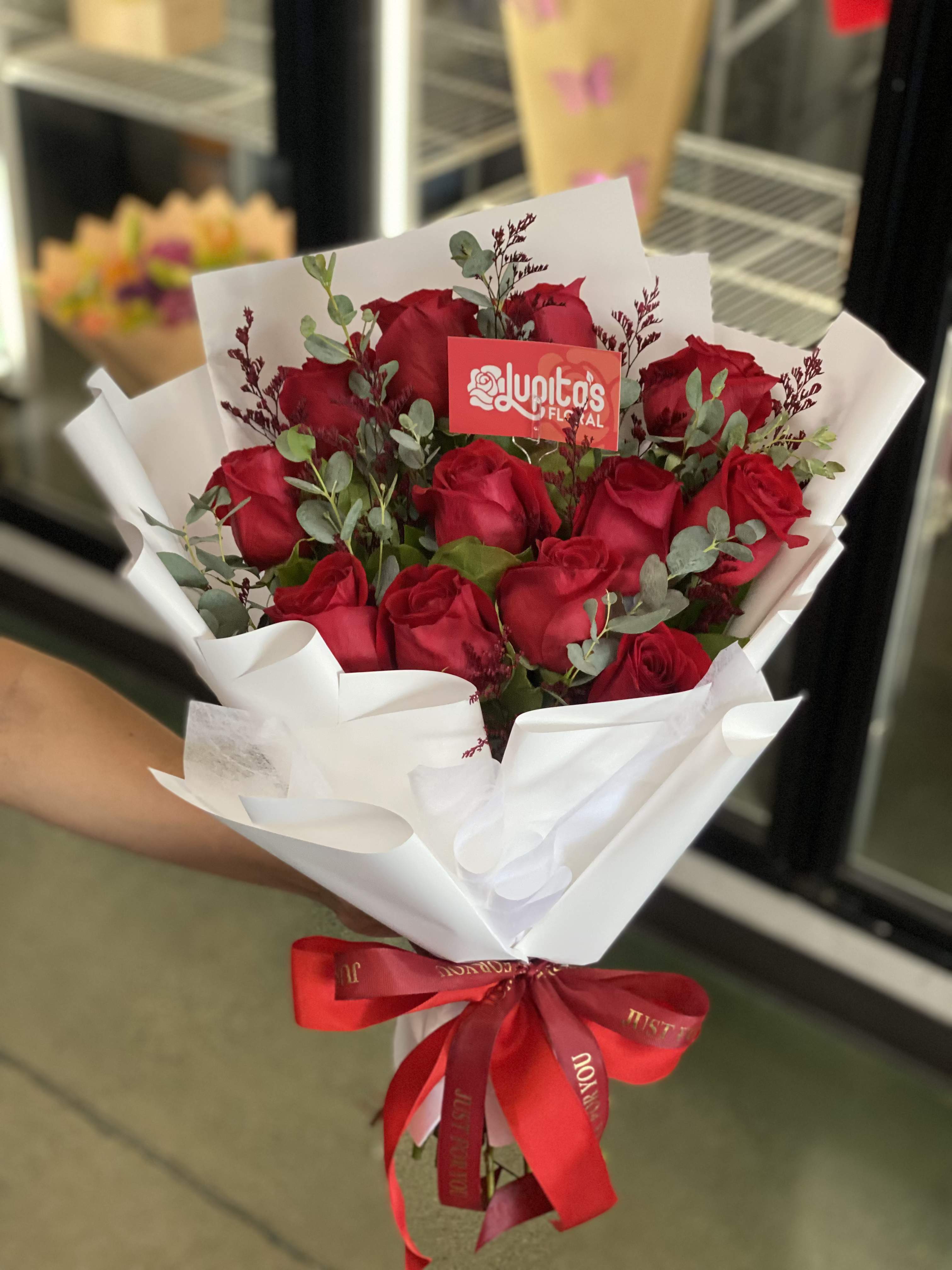 Bouquet of red roses wrapped in white paper with a red ribbon