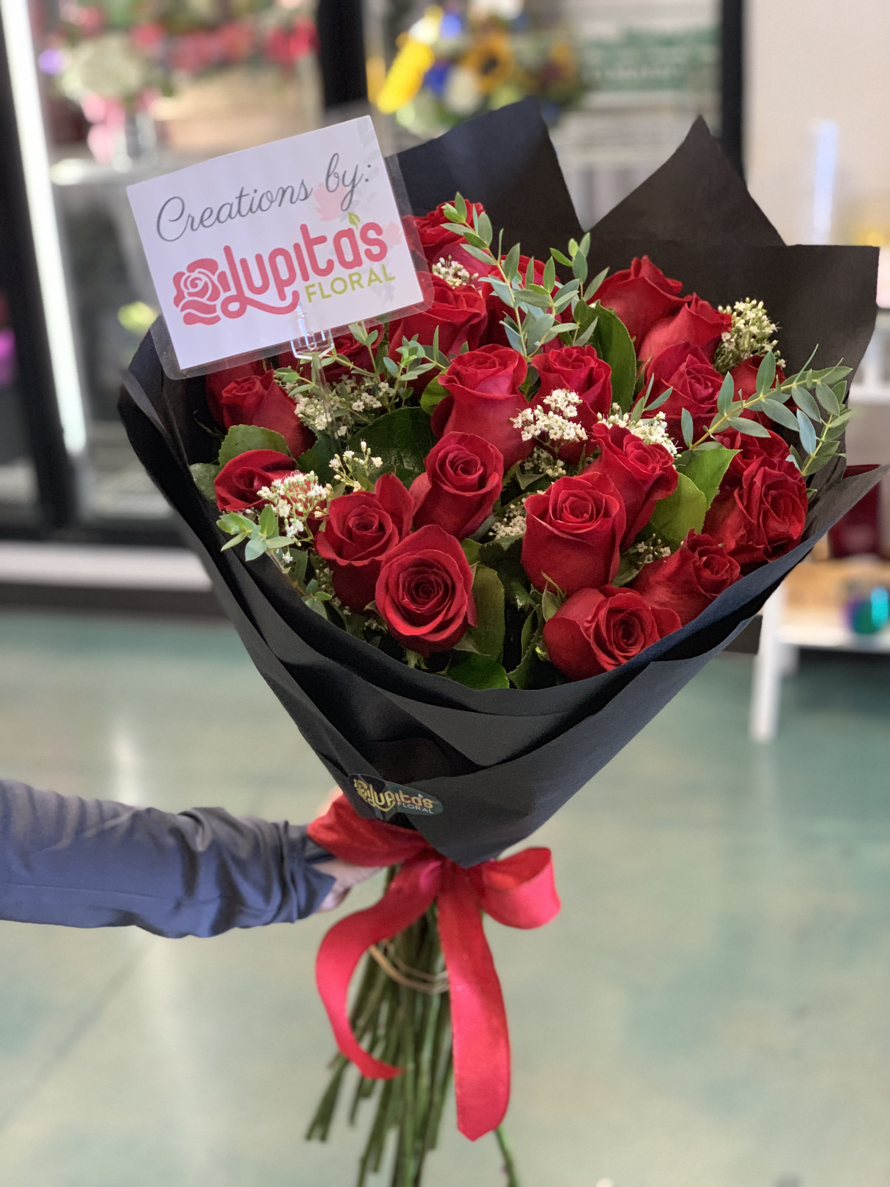 Bouquet of red roses wrapped in black paper with a red ribbon