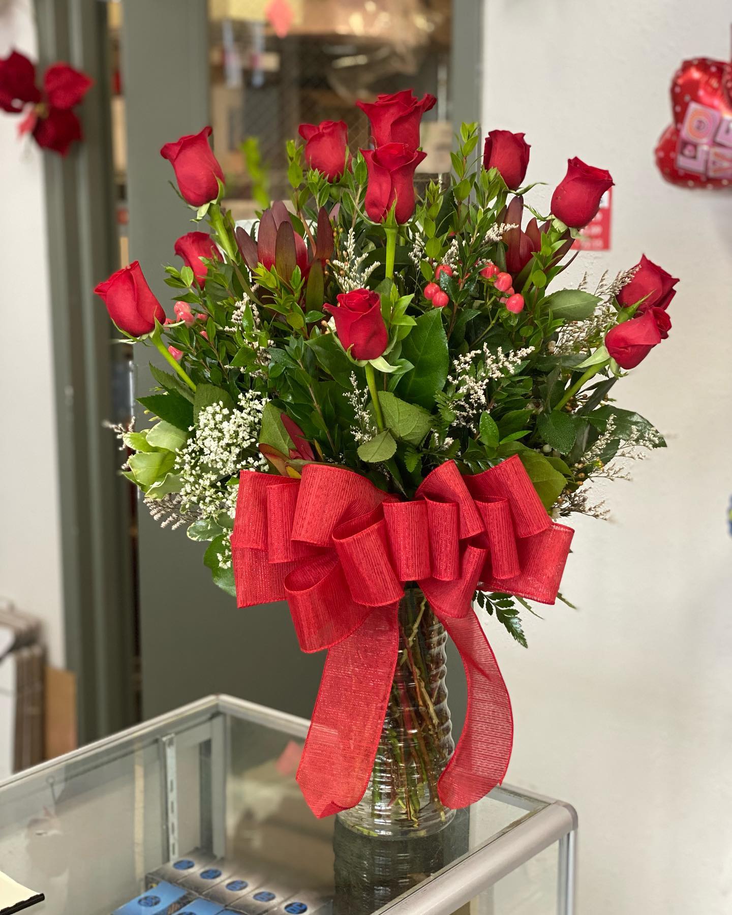 Bouquet of red roses in a clear glass vase with a large red ribbon