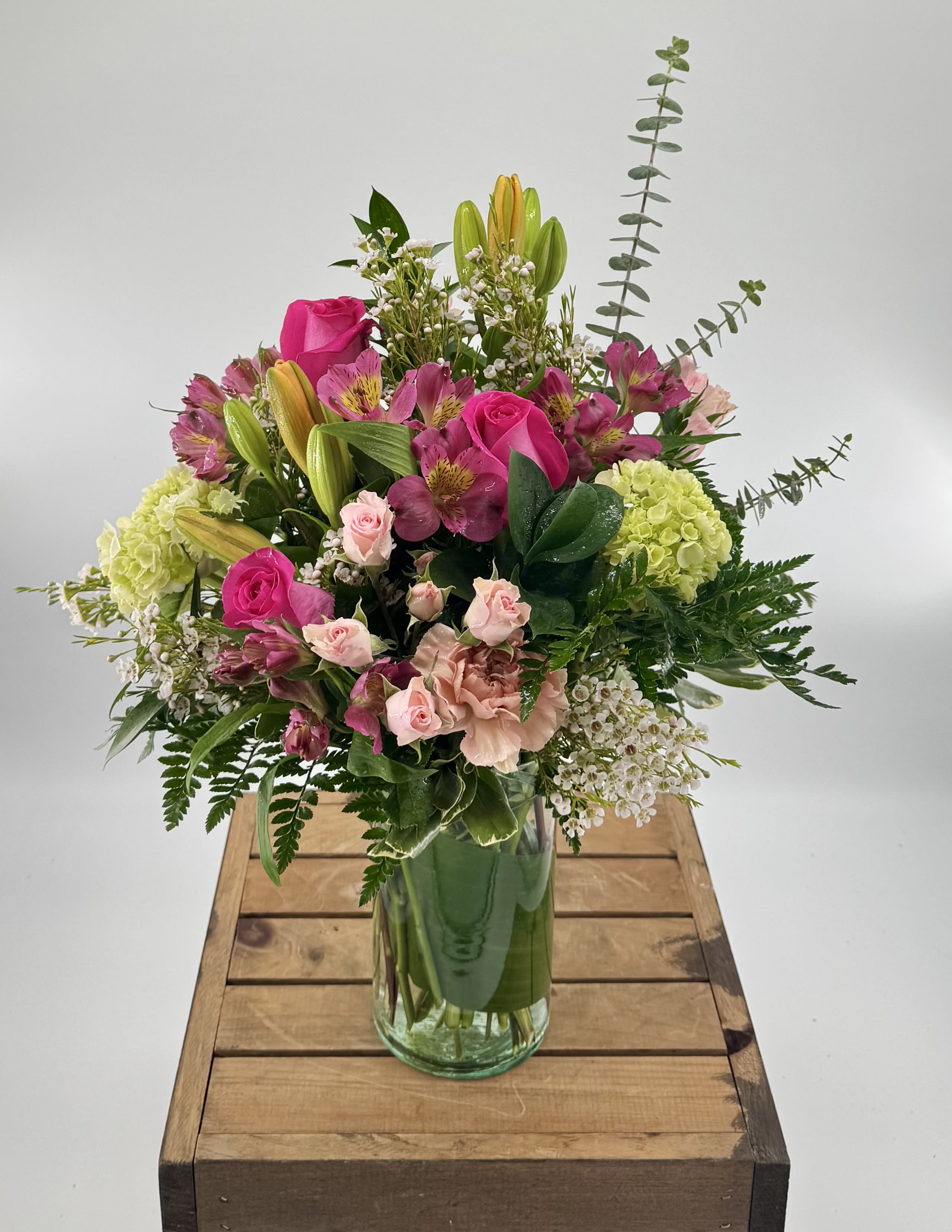 Mixed pink and green floral arrangement in a glass vase