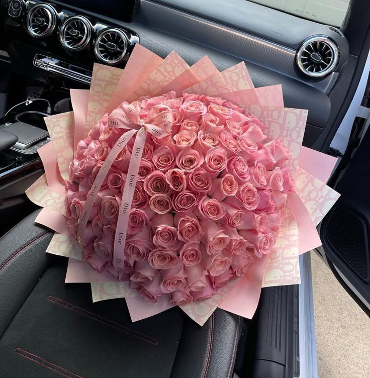 Large bouquet of pink roses wrapped in pink paper with a ribbon