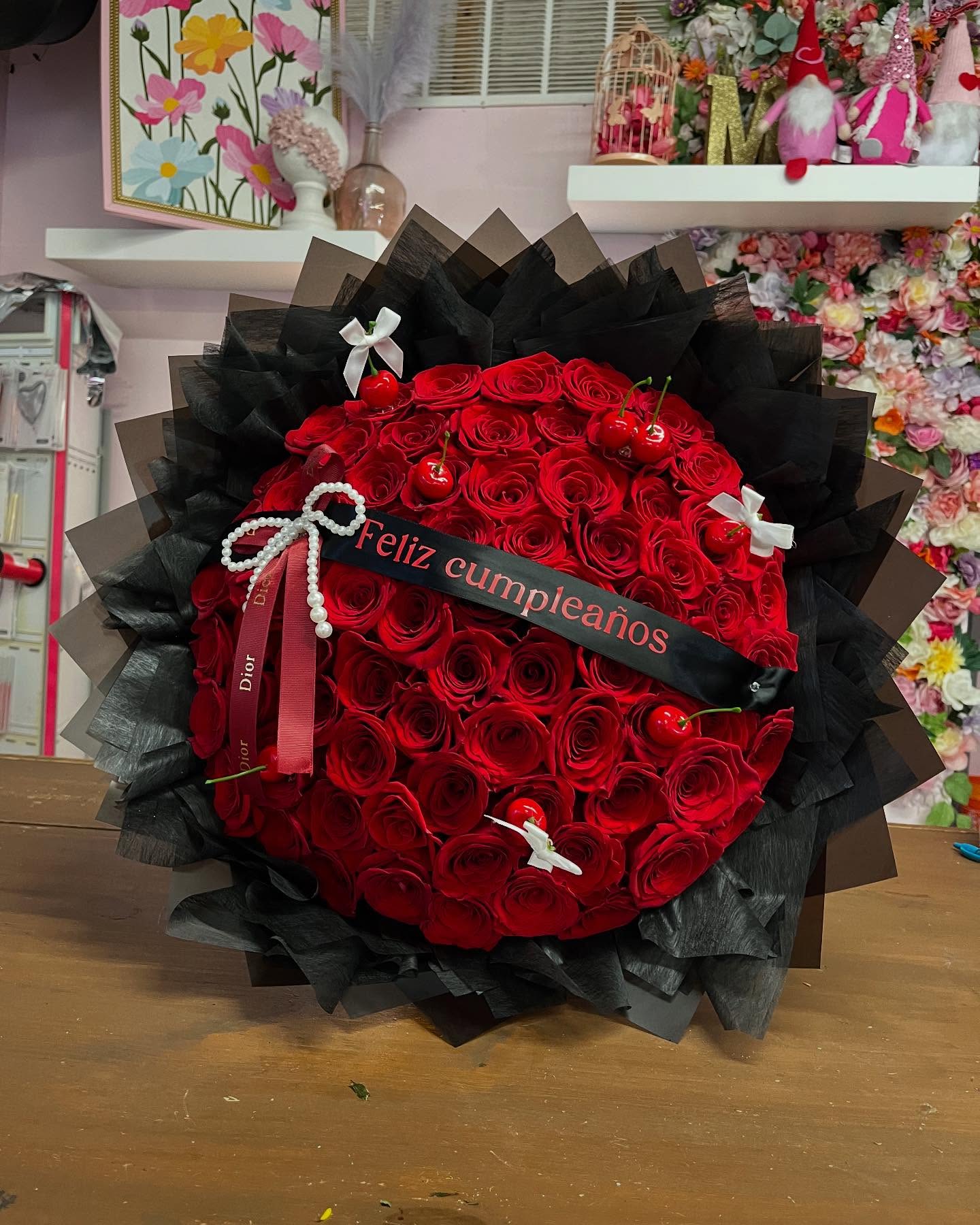 Large bouquet of red roses wrapped in black paper with a birthday ribbon