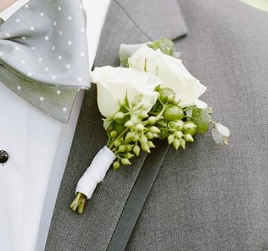 White rose boutonniere pinned to a gray suit jacket