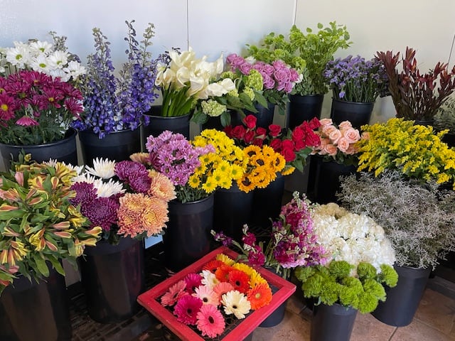 Assorted flower buckets with colorful blooms and a tray of gerbera daisies