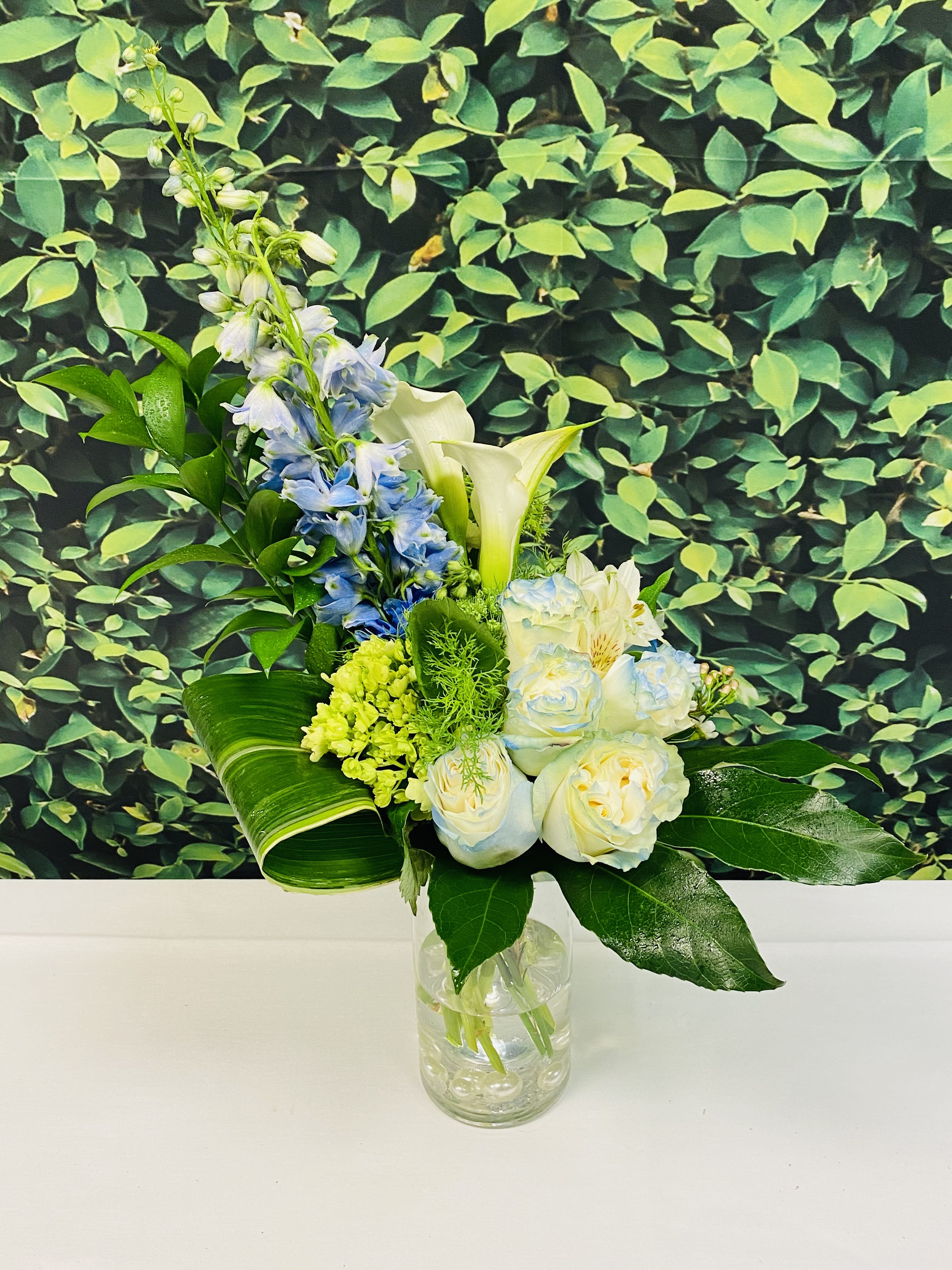 Blue and white flowers arranged in a clear glass vase