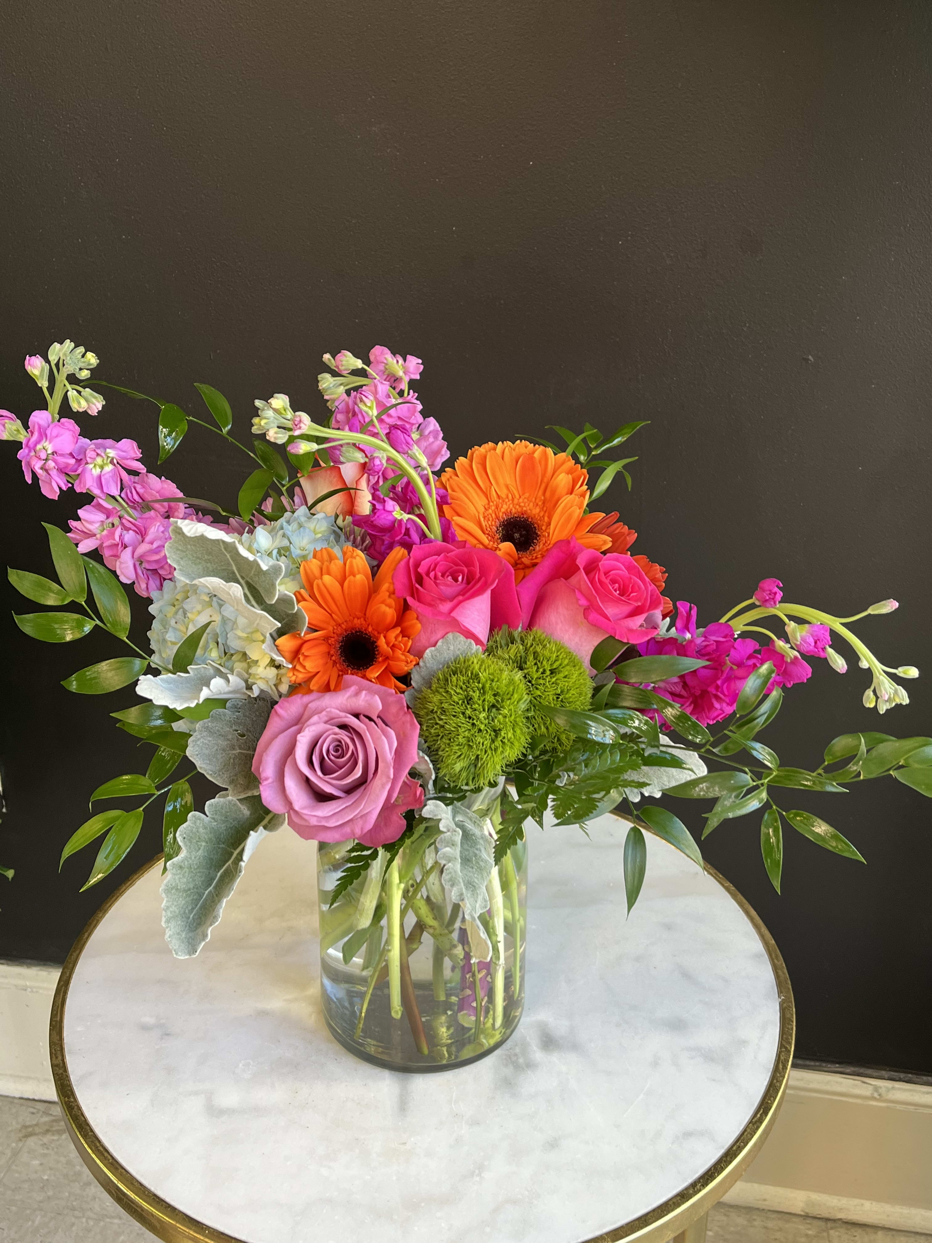 Mixed bouquet in a clear glass vase with pink roses and orange gerbera daisies