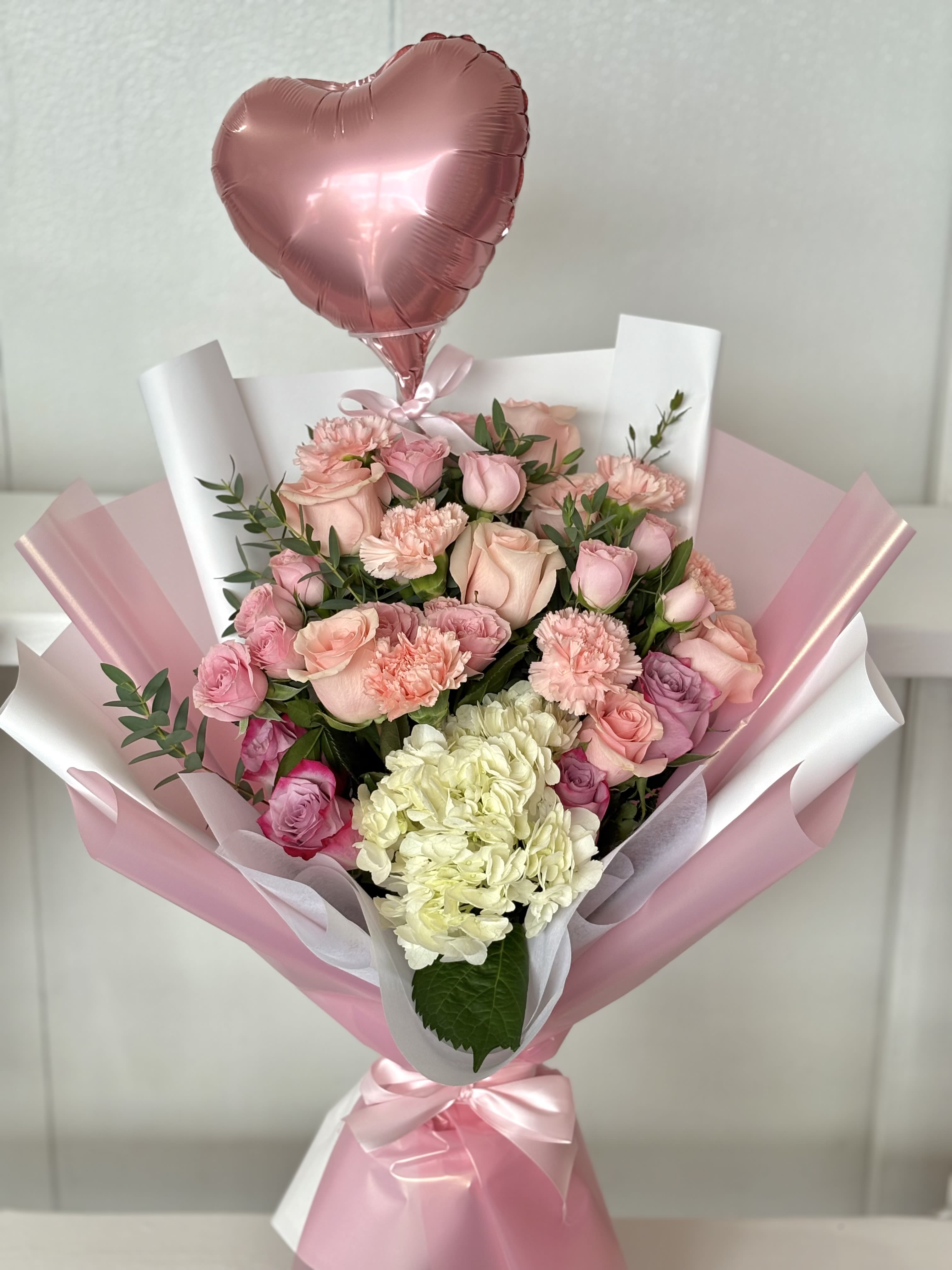 Pink bouquet with roses, carnations, hydrangea, and a heart balloon