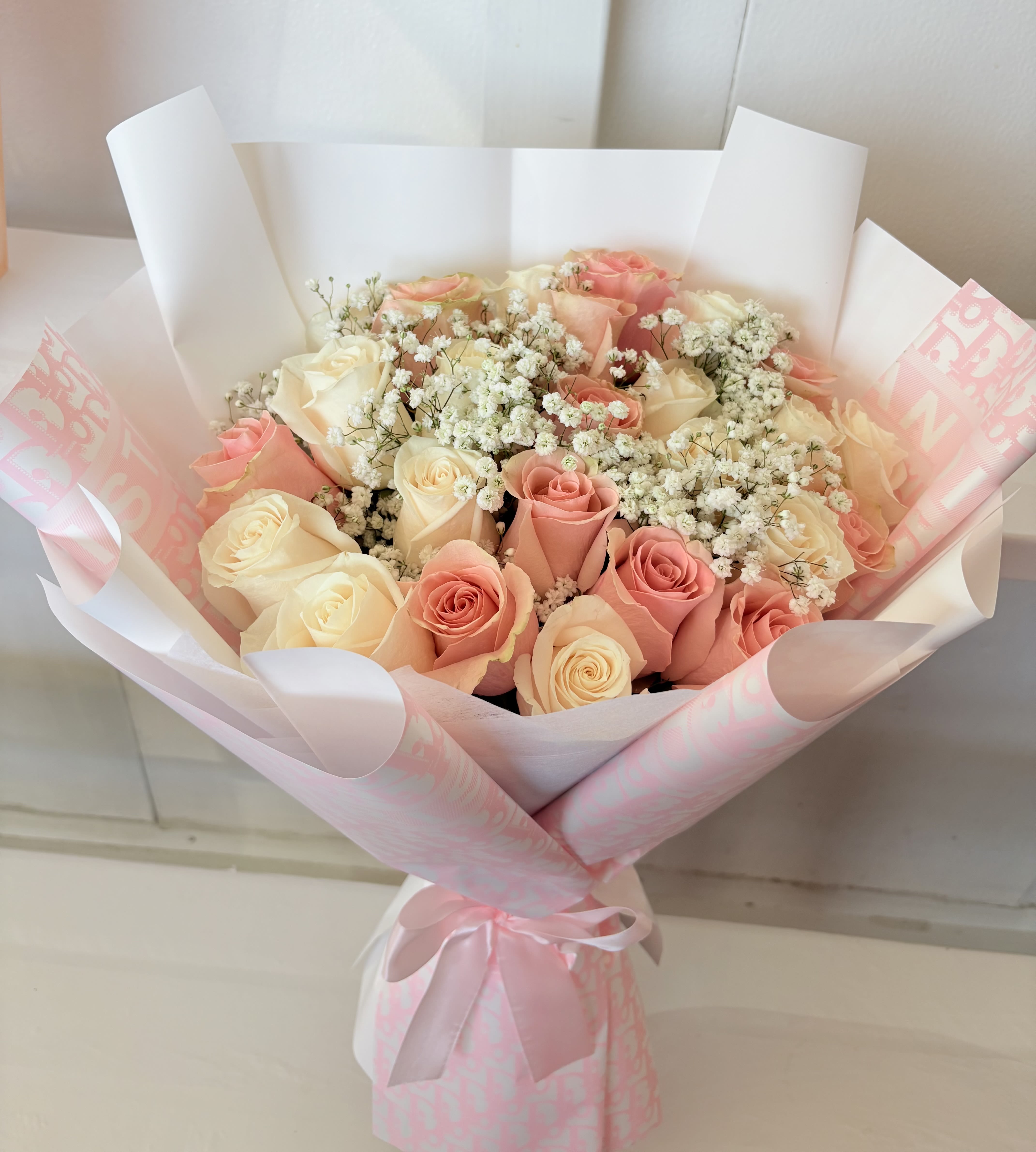 Bouquet of pink and cream roses with baby's breath in pink wrapping