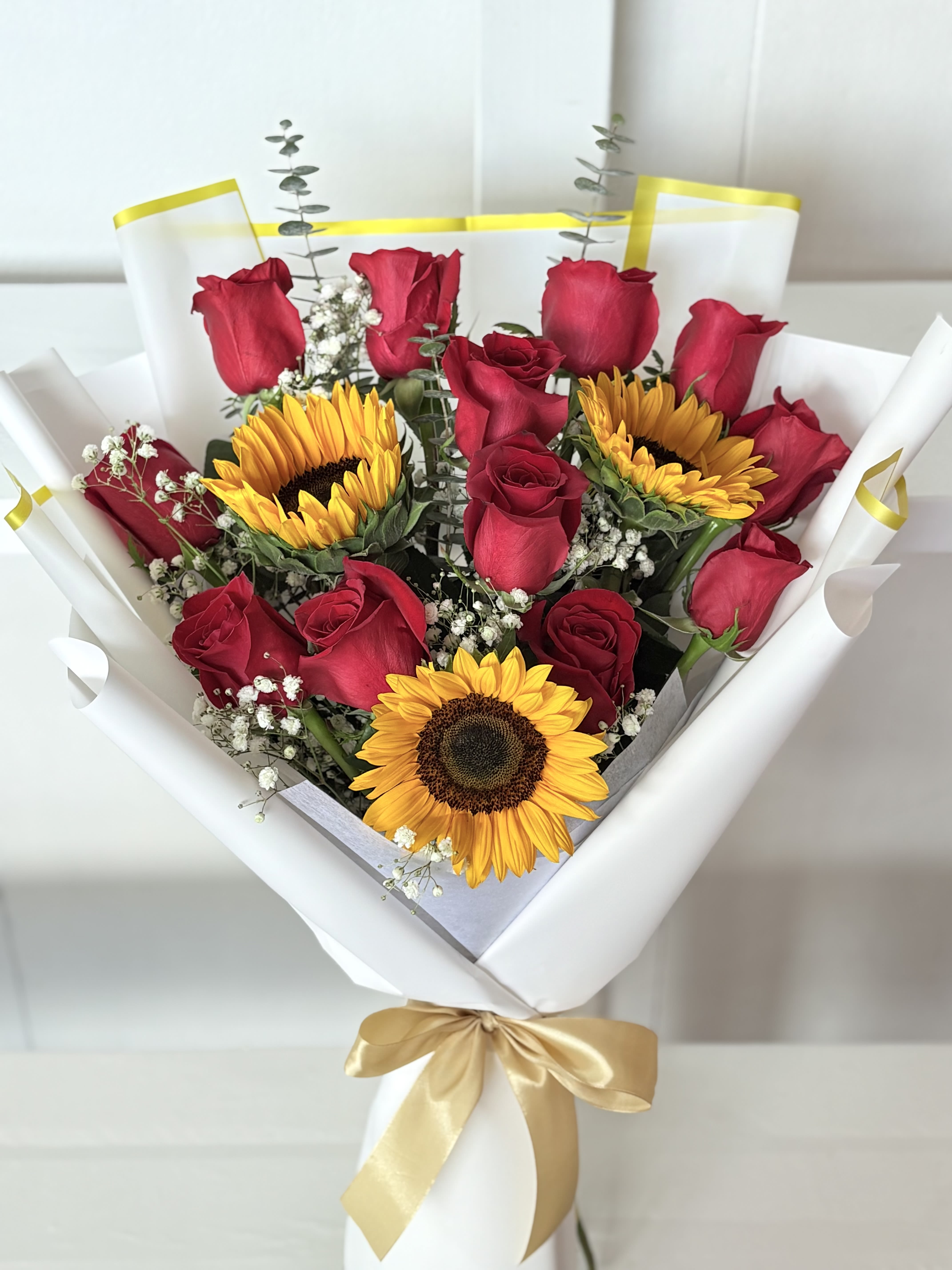 Bouquet of red roses and sunflowers wrapped in white paper