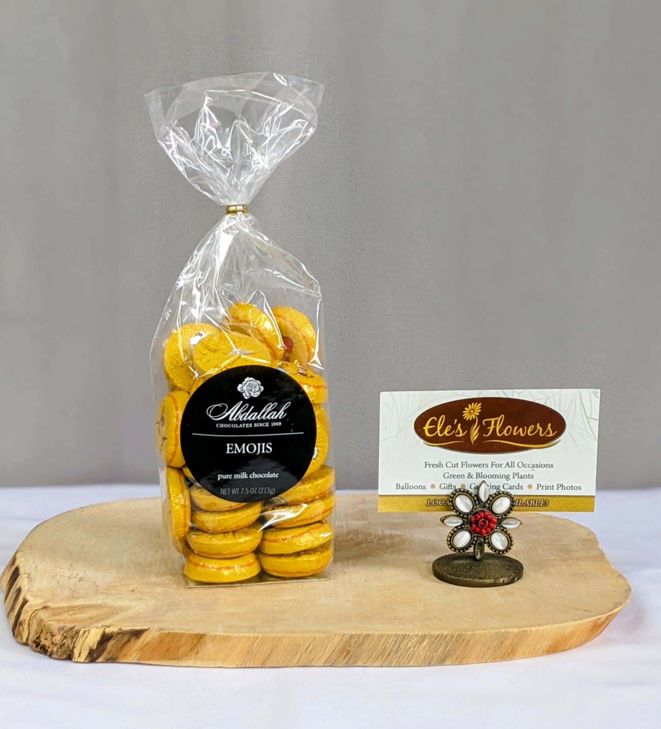 Bag of yellow emoji chocolates on a wood slab with a decorative business card holder