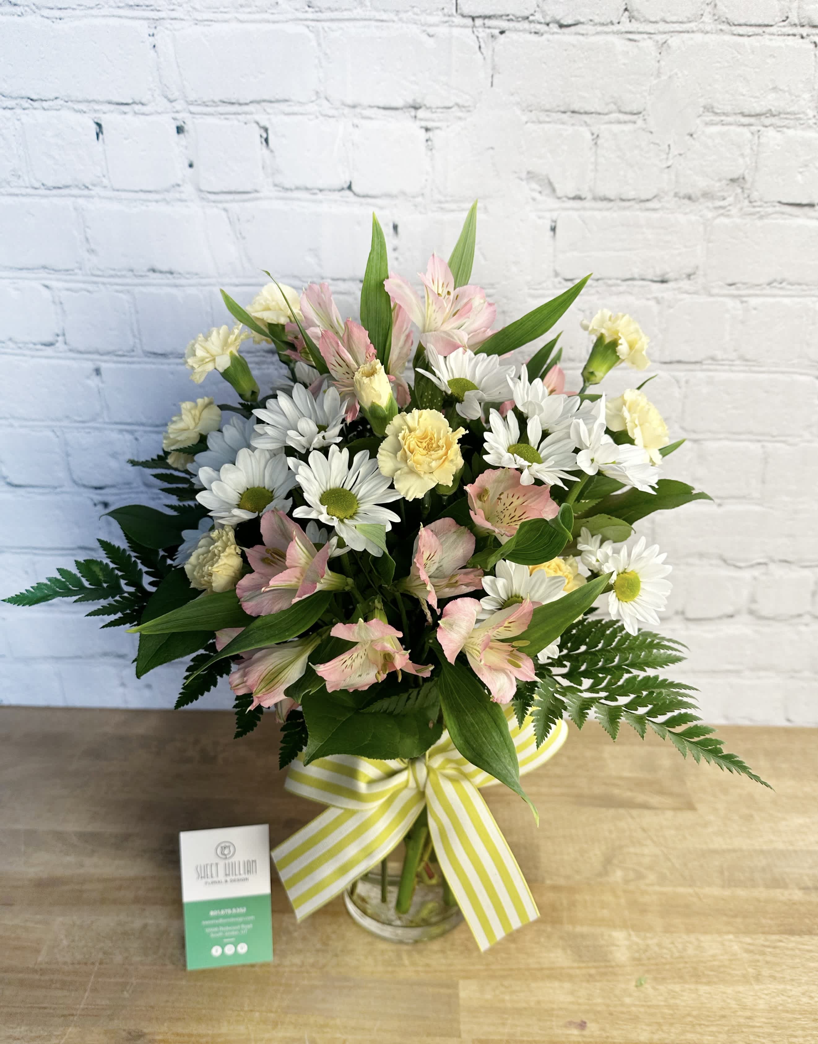 Bouquet of pink alstroemeria, white daisies, and yellow carnations in a glass vase