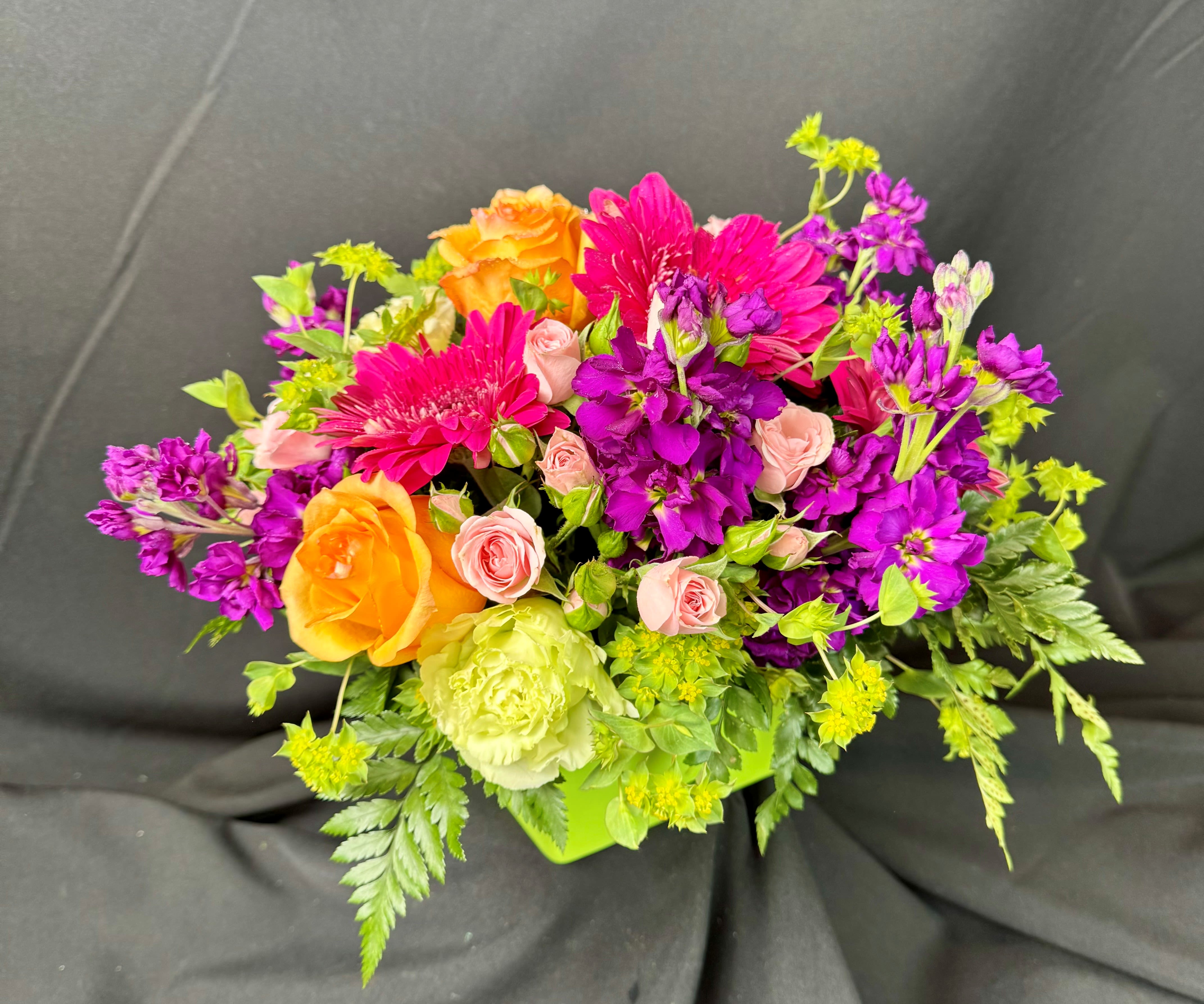 Bright mixed bouquet with orange roses, pink blooms, and purple flowers