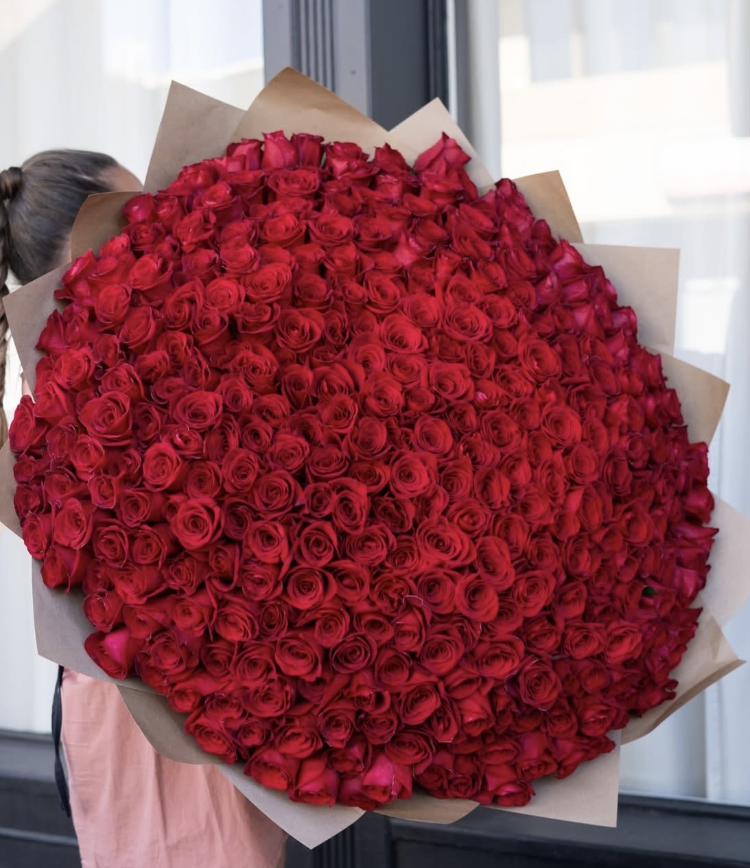 Large bouquet of red roses wrapped in brown paper