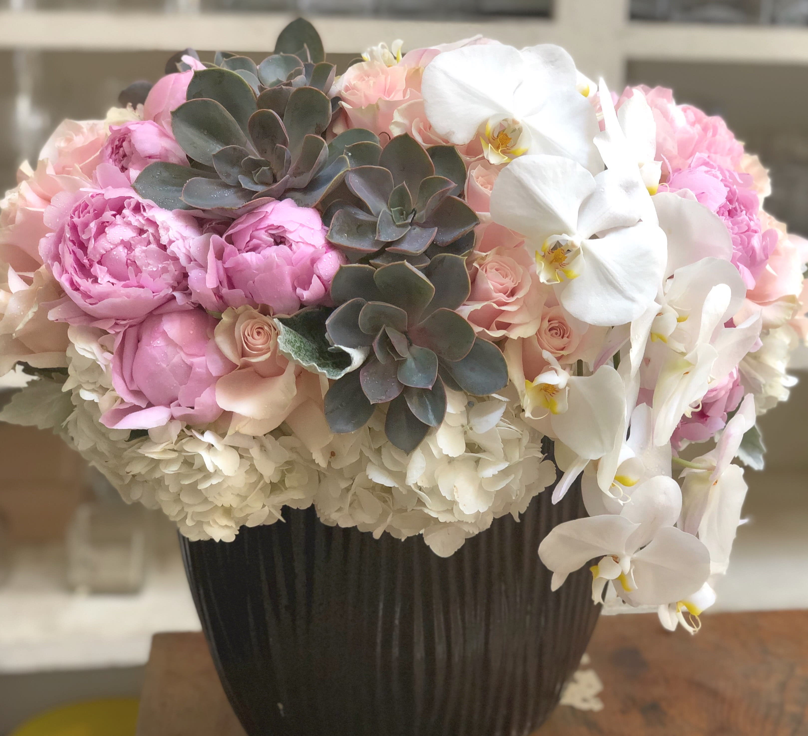 Pink peonies and white orchids in a dark vase