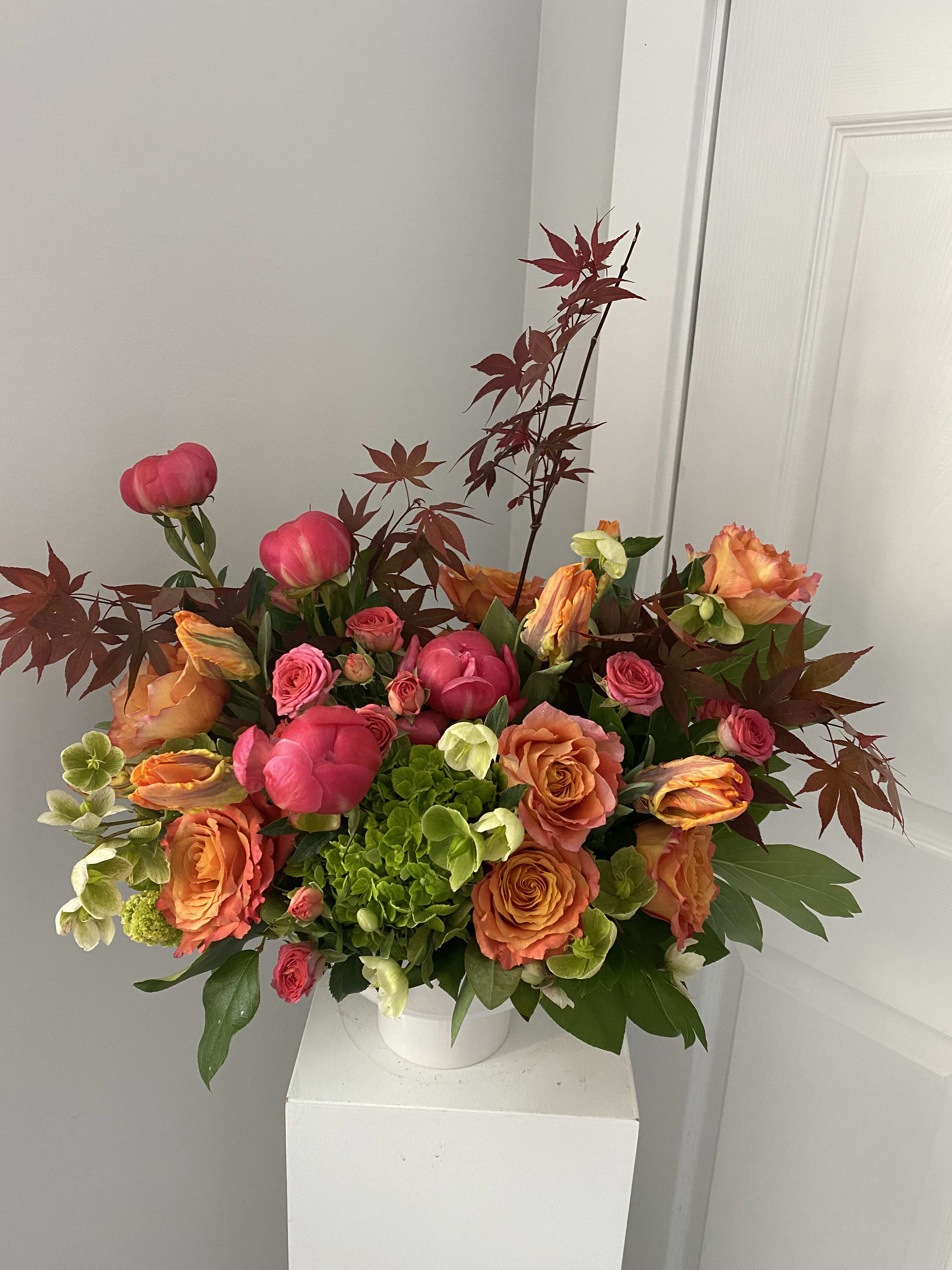 Bouquet of pink and orange roses with green hydrangea in a white vase