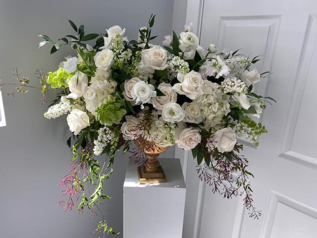 Large white floral arrangement in a gold vase