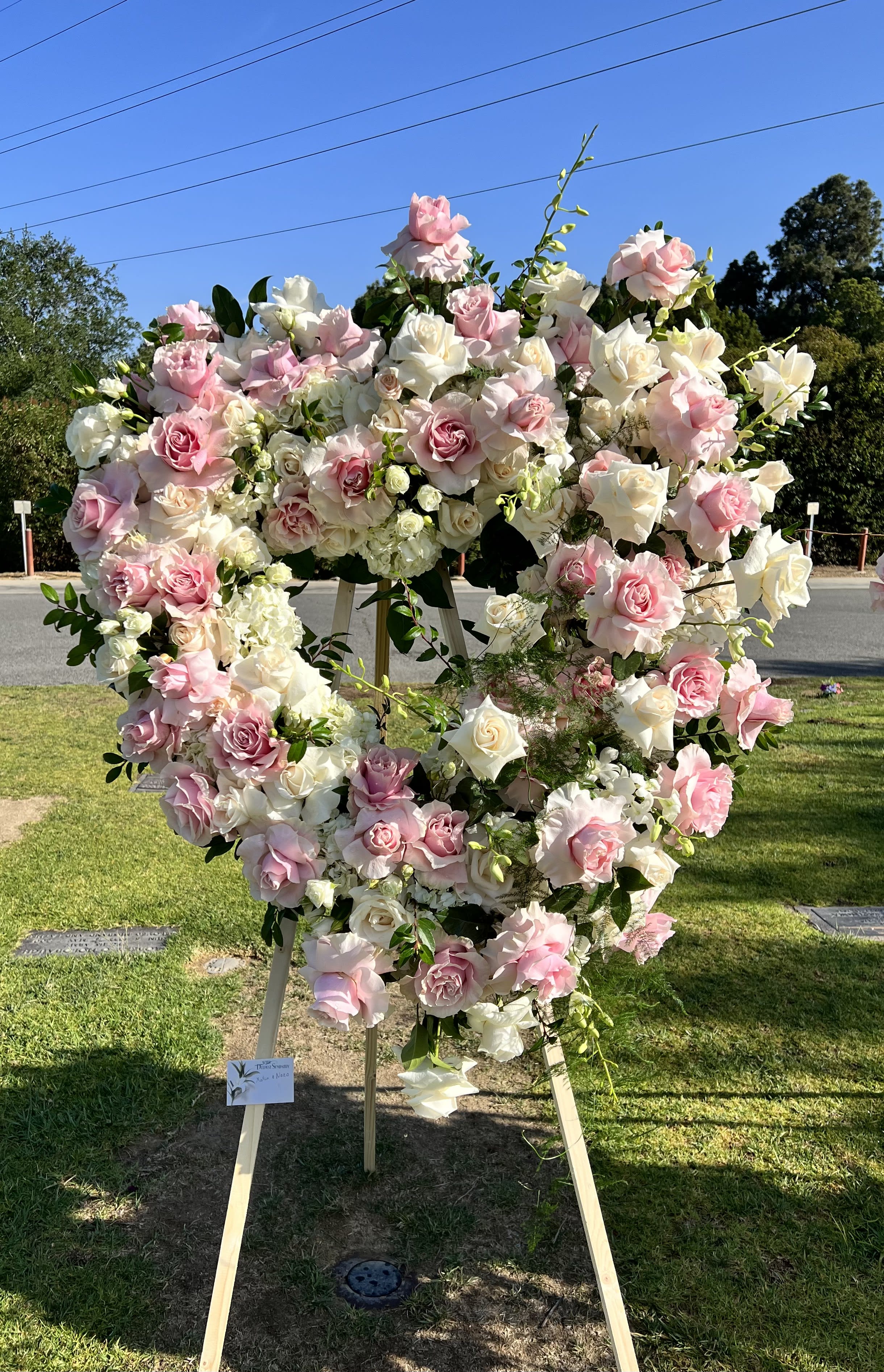 Large heart-shaped floral wreath of pink and white roses on an easel